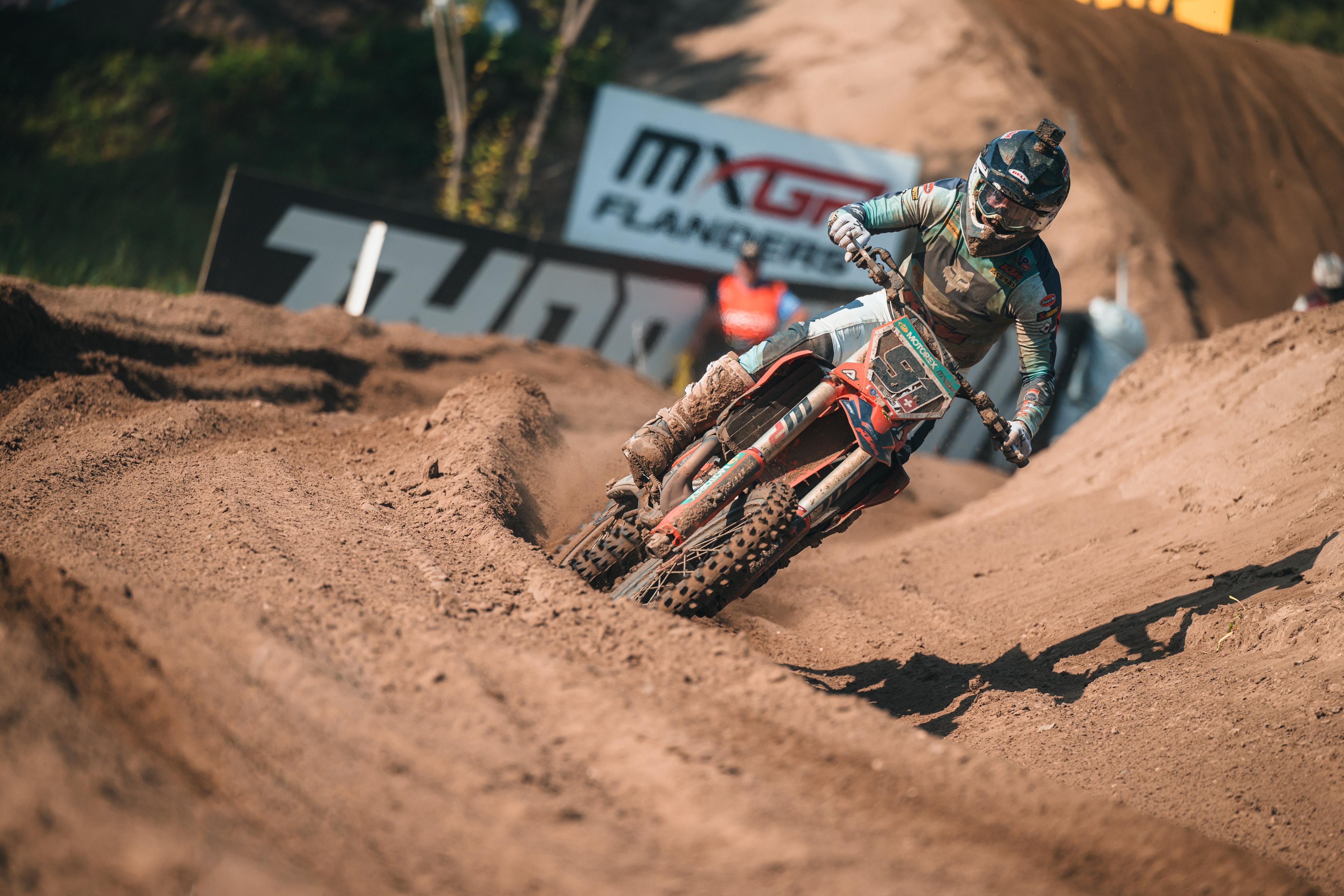 Jeremy Seewer railing a muddy rutted corner on his number 91 Van Venrooy KTM during an MXGP race