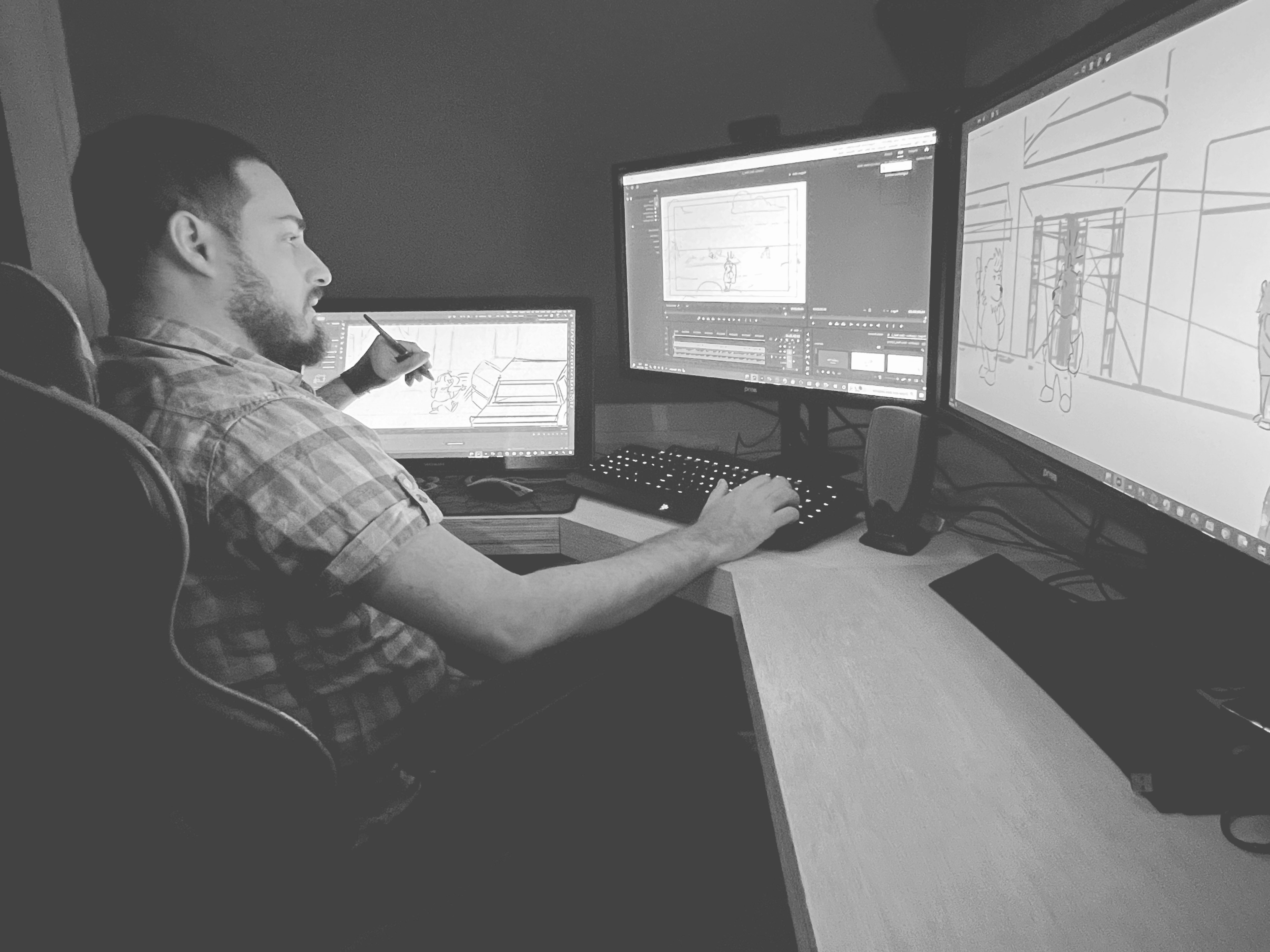 Black and white photo of two people looking at a computer screen with papers on wall