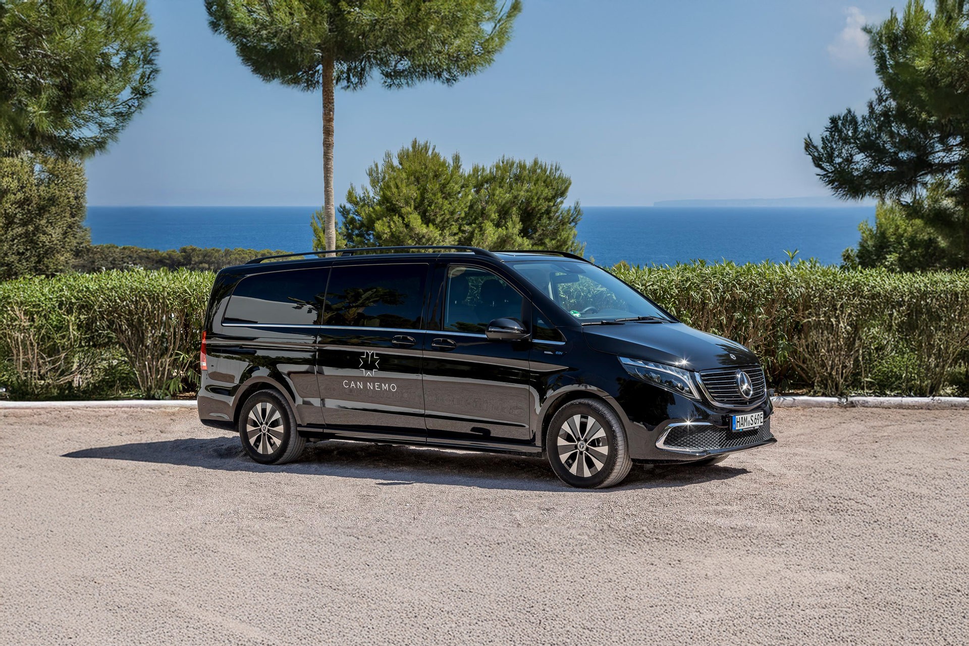 Can Nemo branded luxury chauffeur van parked with Mediterranean sea view in Ibiza.