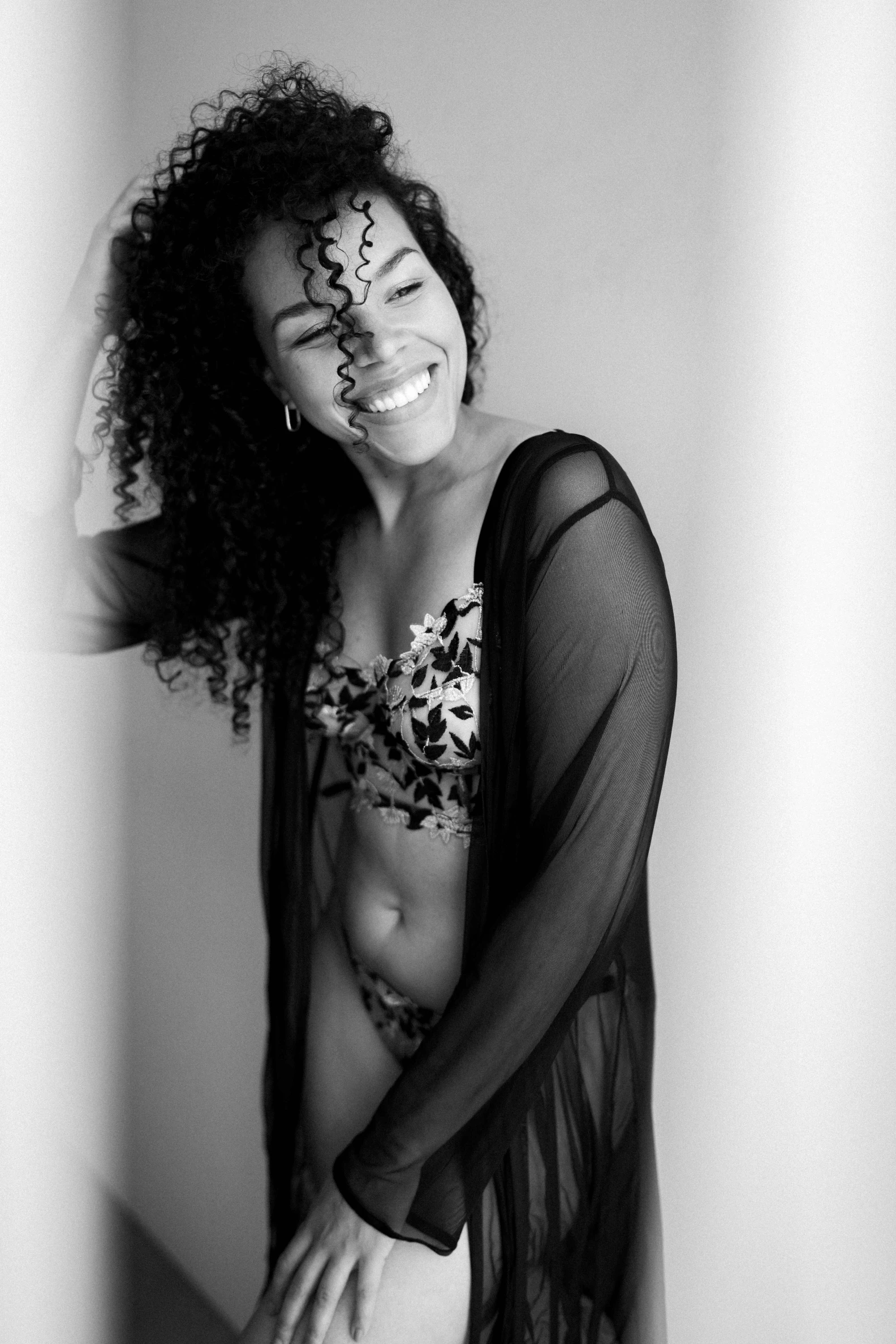 Grinning woman in elegant lingerie, embracing self-love in Swiss boudoir photography.