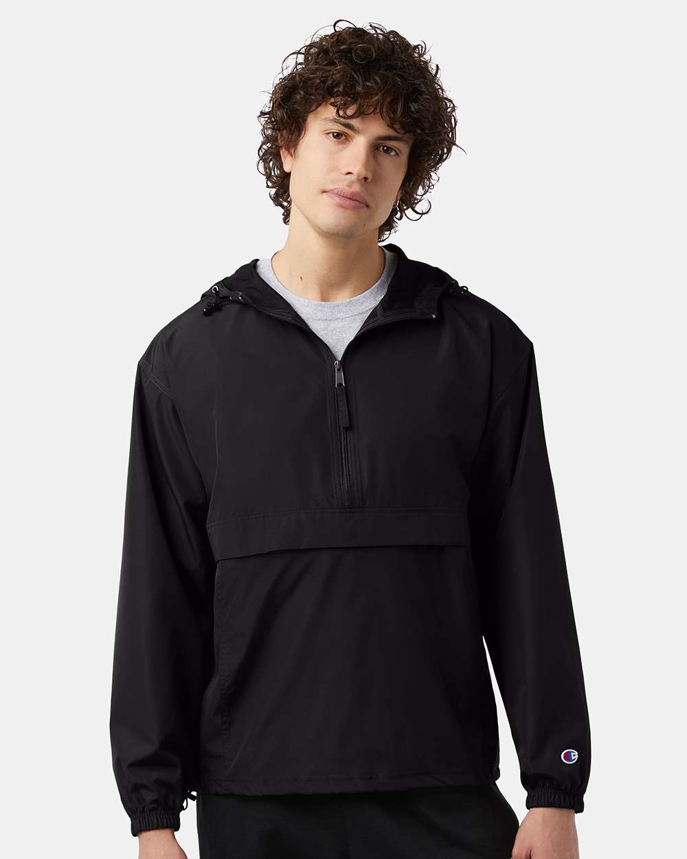 A black anorak jacket with the champion logo on the left cuff on a model.