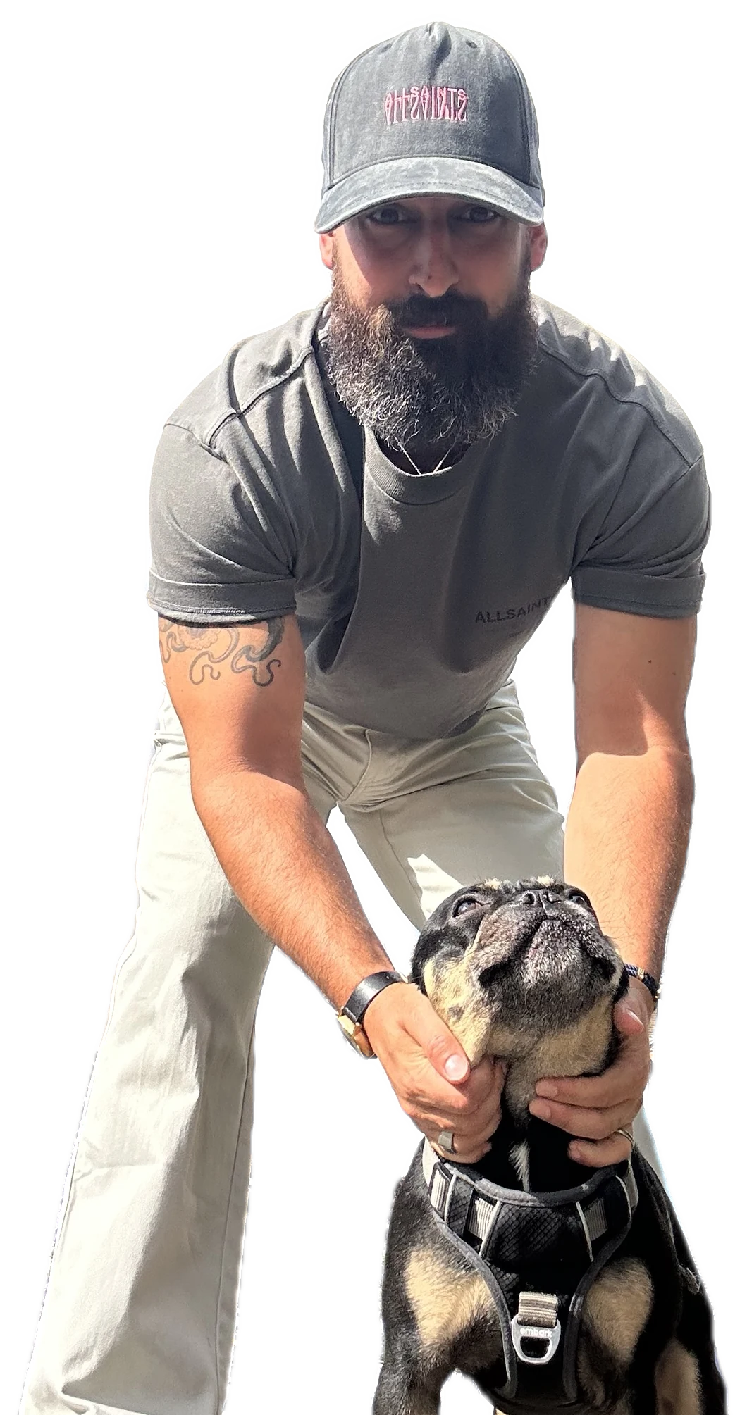 Jamie Lyons, in a cap, crouching on a pavement and holding his dog Brûlée