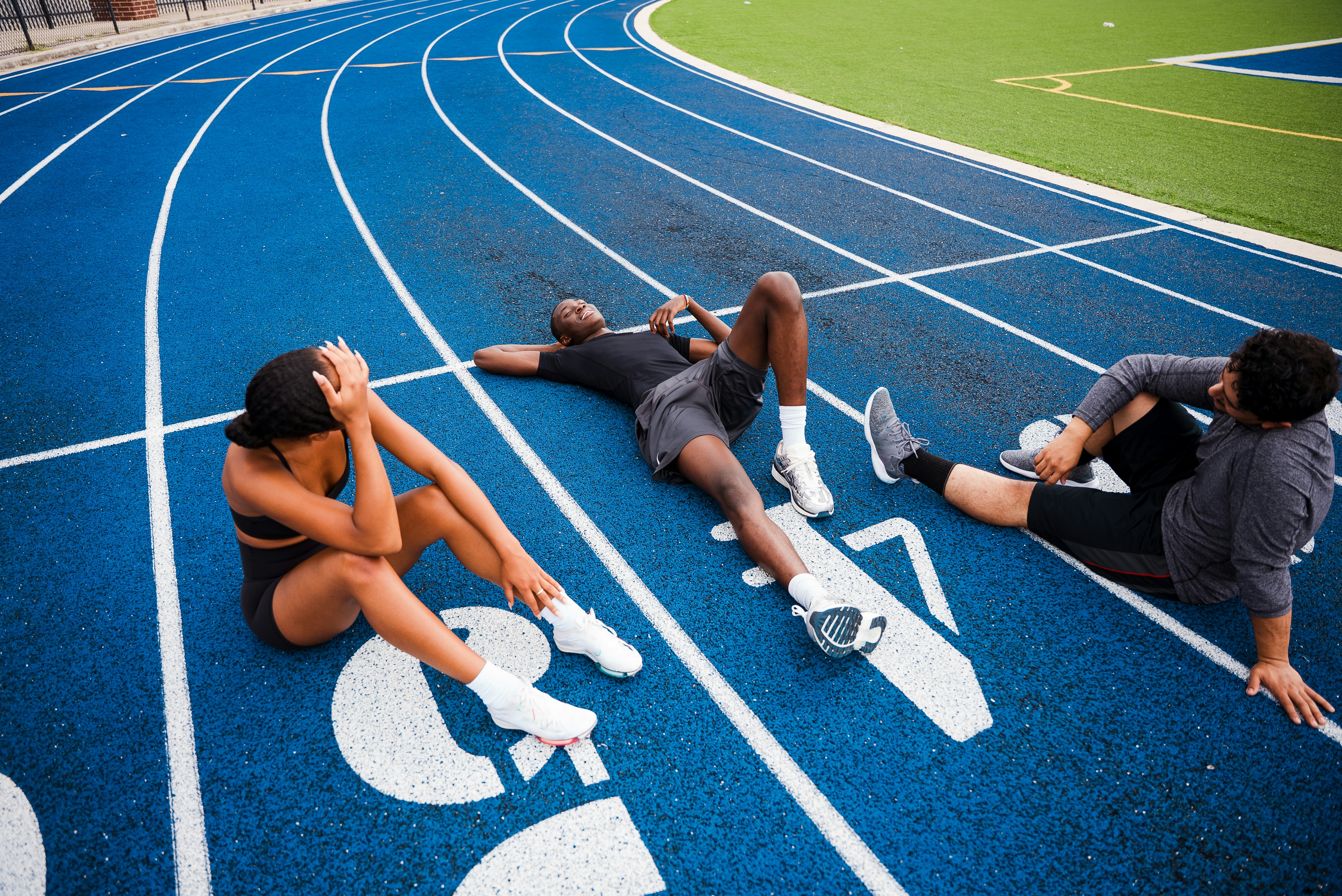 Athletes resting on a blue running track.