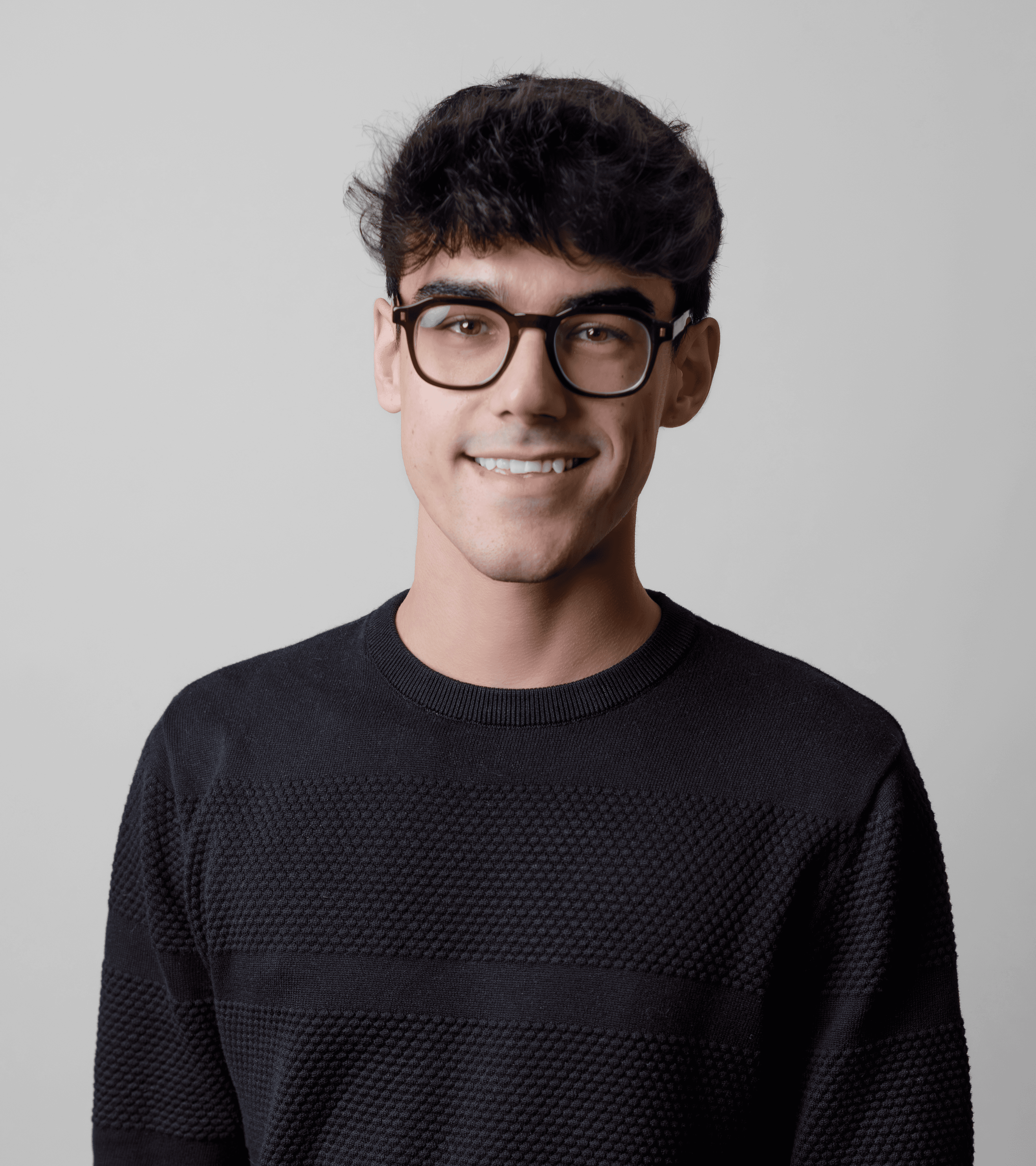 A thoughtful young person with dark hair gazes to the side, captured in soft black and white lighting.