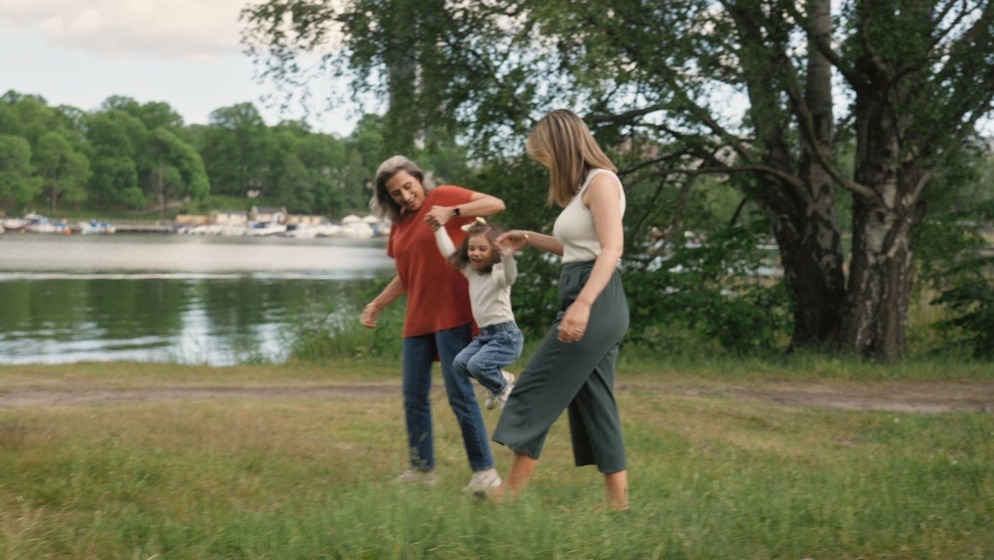 Mamma, mormor och barn leker på en äng vid vattnet, ur filmen Att bli äldre