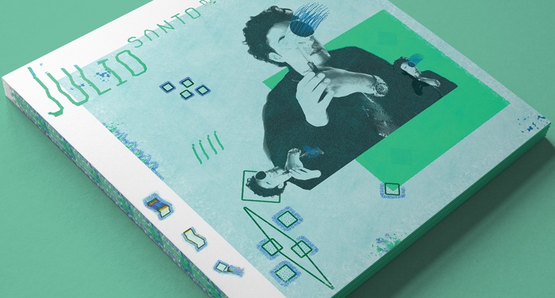A green colored painting with some shapes and a photo of a man. On it there is the text: Julio Santo.