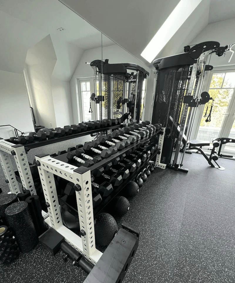 Luxury home gym featuring dumbbell racks and selectorized strength machines in a professionally designed Canadian home gym.