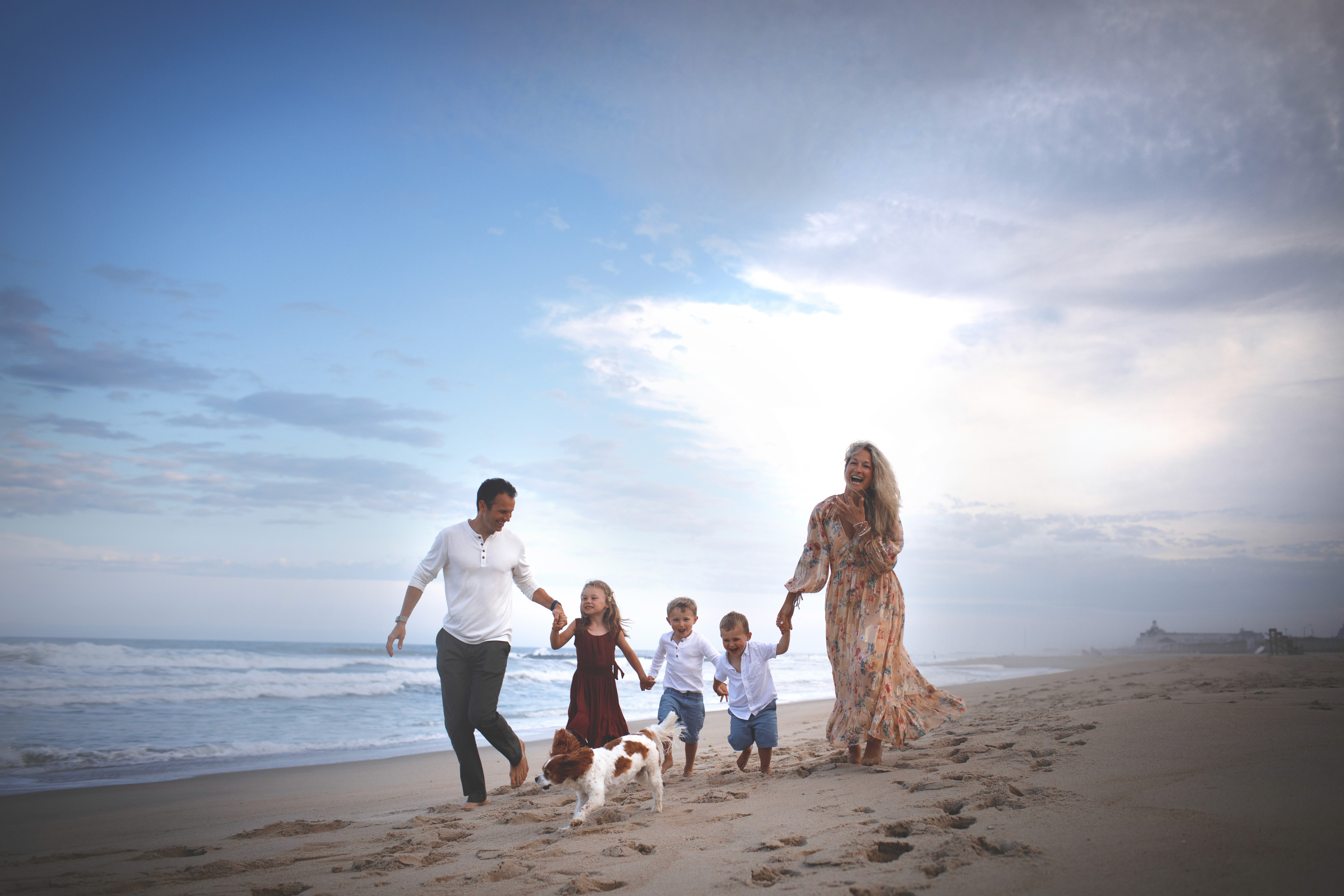Family walking together along the shoreline during a playful beach session