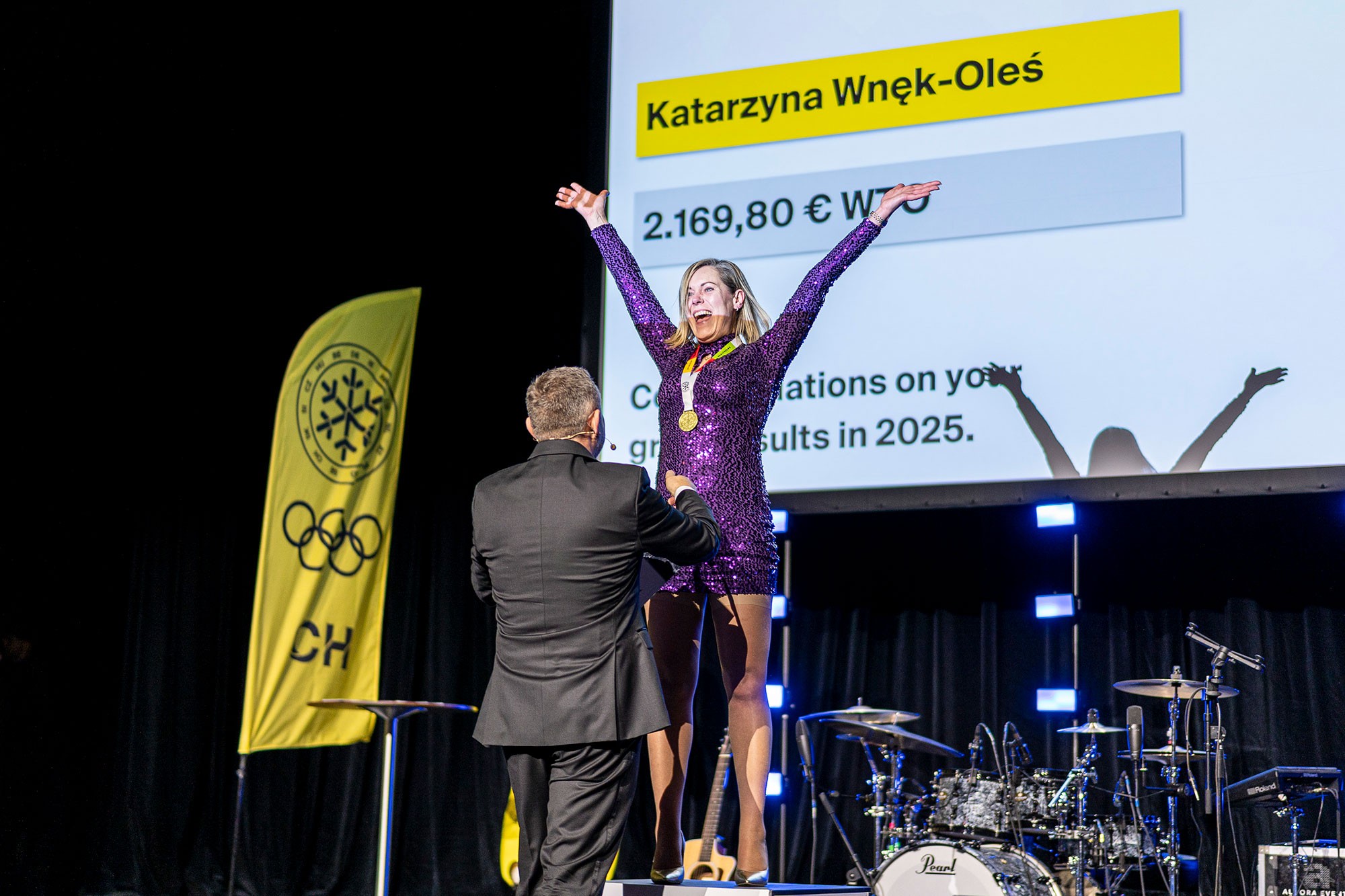 Woman celebrating on stage after receiving an award during a corporate sales conference gala evening.