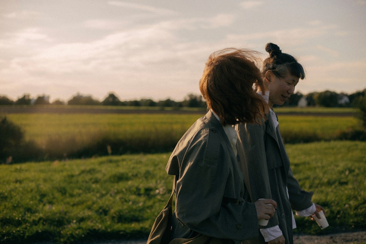 Two people walking side-by-side on a road through agricultural farmlands.