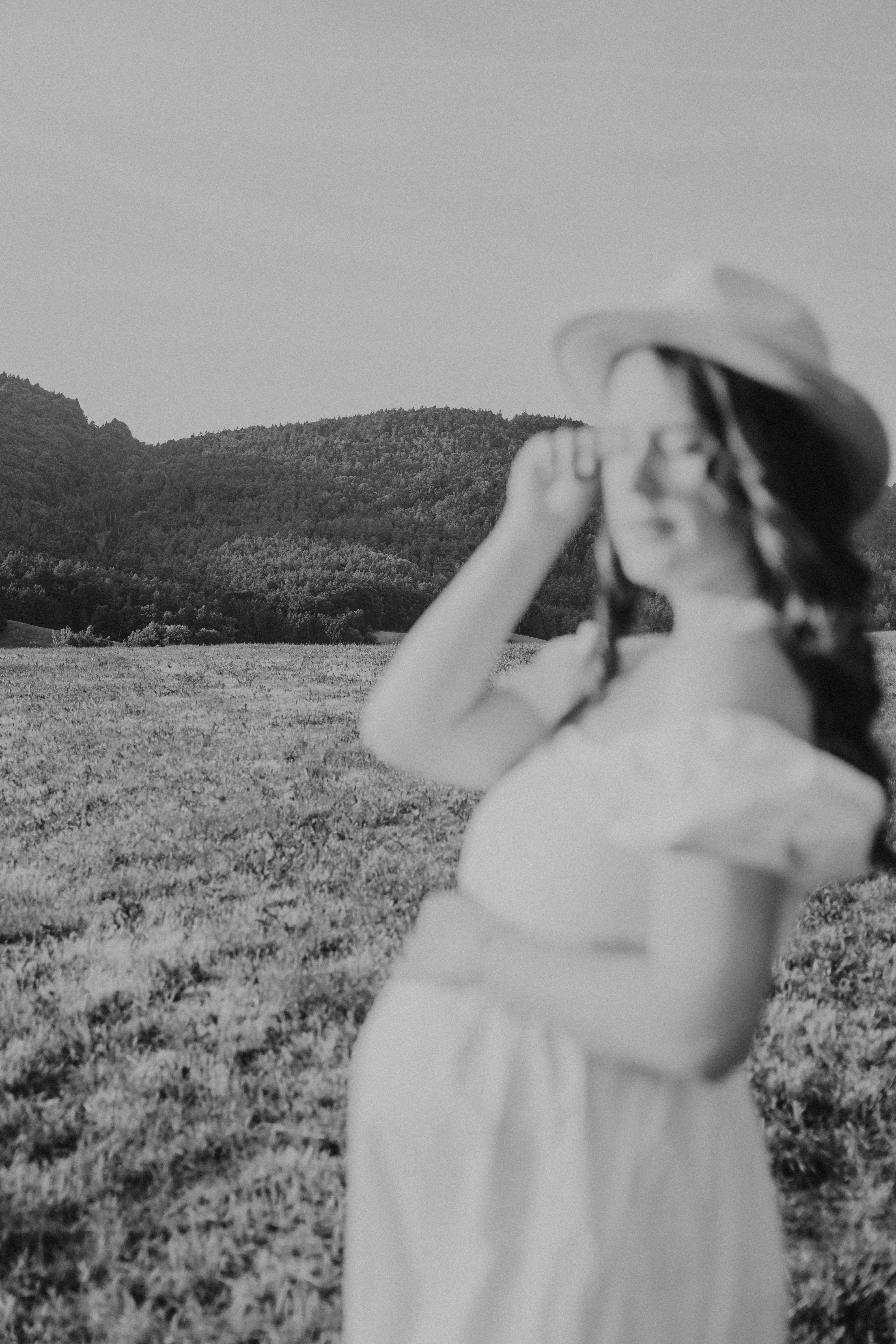 Schwarzweiß Schwangerschaftsfotografie in Bogen – schwangere Frau mit Hut bei natürlichem Outdoor Shooting.