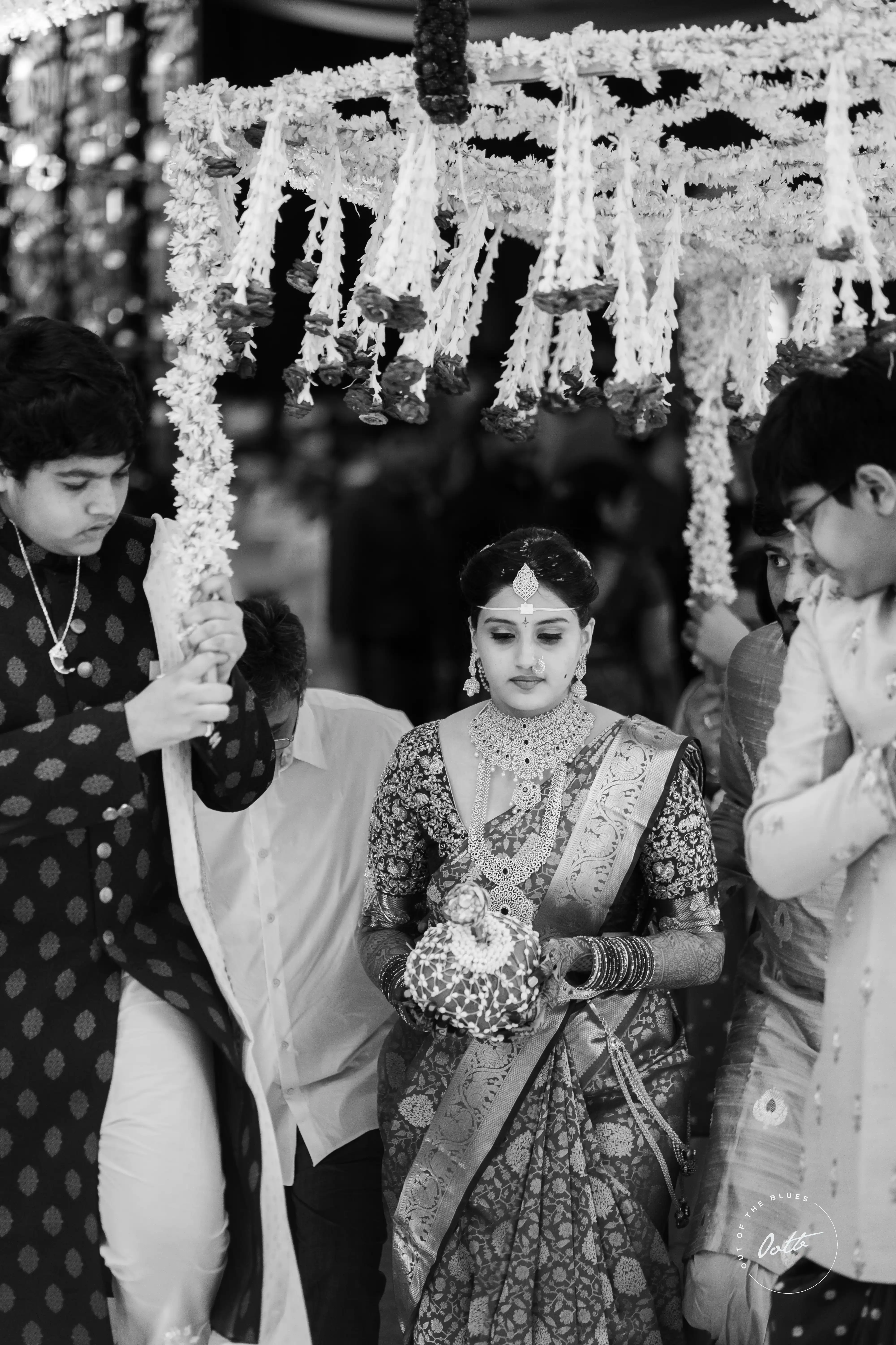 Tanya gracefully enters her wedding, surrounded by family. Black & white Fine Art Wedding Photography in Hyderabad by Out of The Blues.