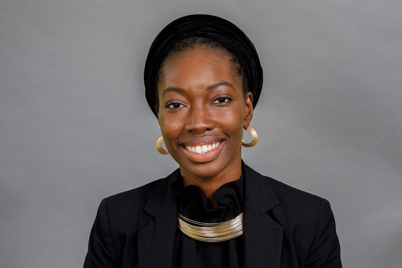 woman in black blazer covering her face with her hand
