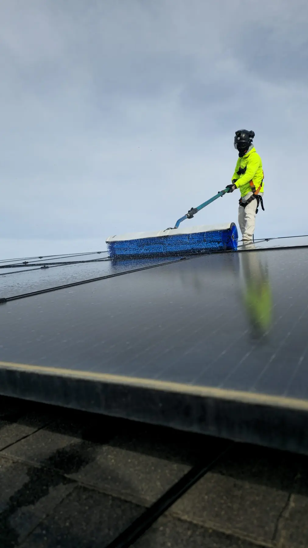 Technician cleaning a rooftop array with a long pole brush | Premier Solar Service, serving Tracy, CA
