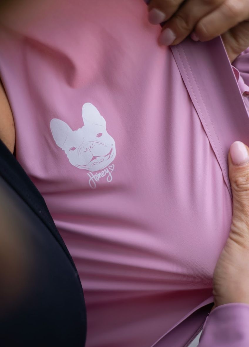 Close-up of-a-light-pink-cycling-top- pulled-open-to-show-the-hidden- white-French-Bulldog-graphic-with- Honey=text-on-the-inside-lining