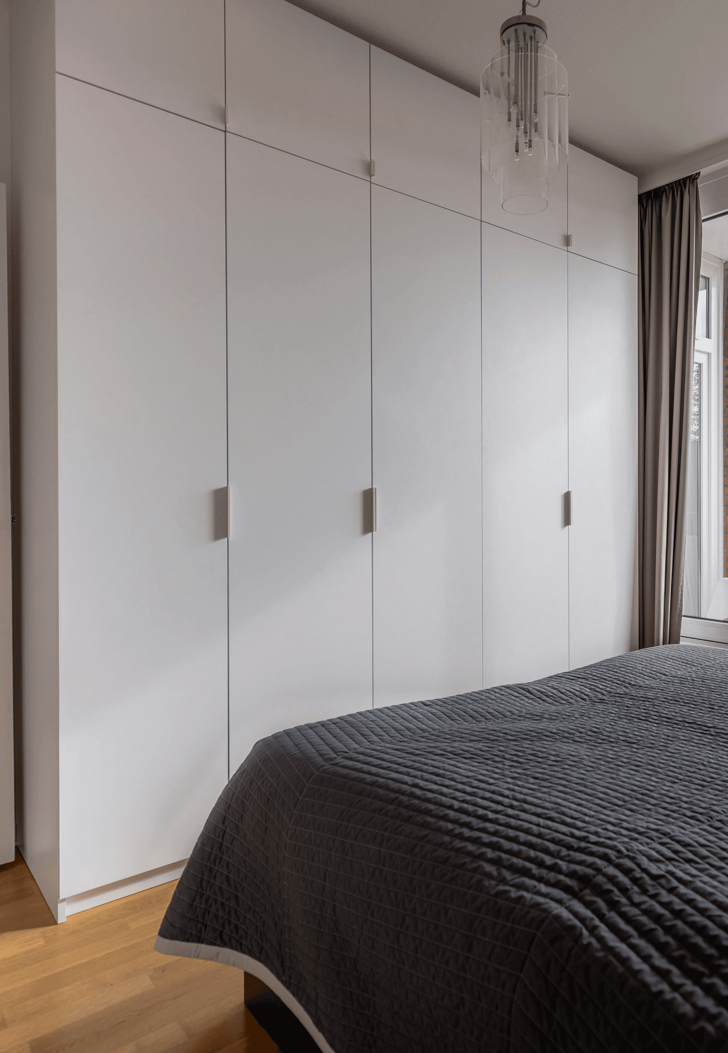 Bedroom with built-in white wardrobes, large window, and contemporary interior design
