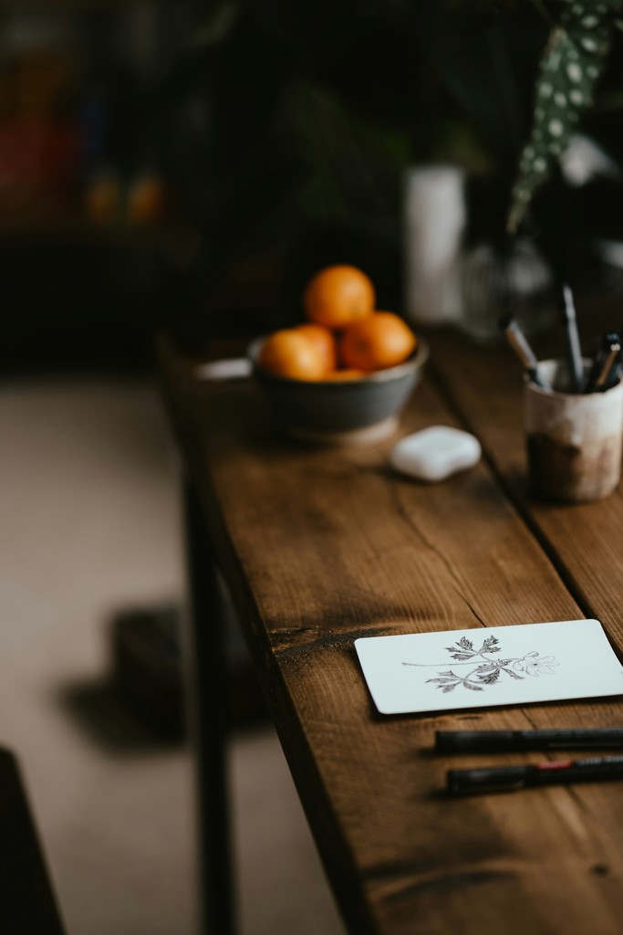 a wooden table topped with a bowl of oranges