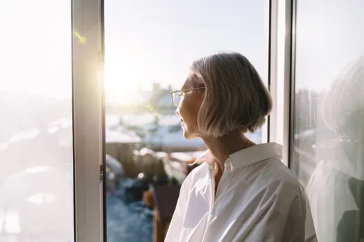 grey haired woman looking out of window