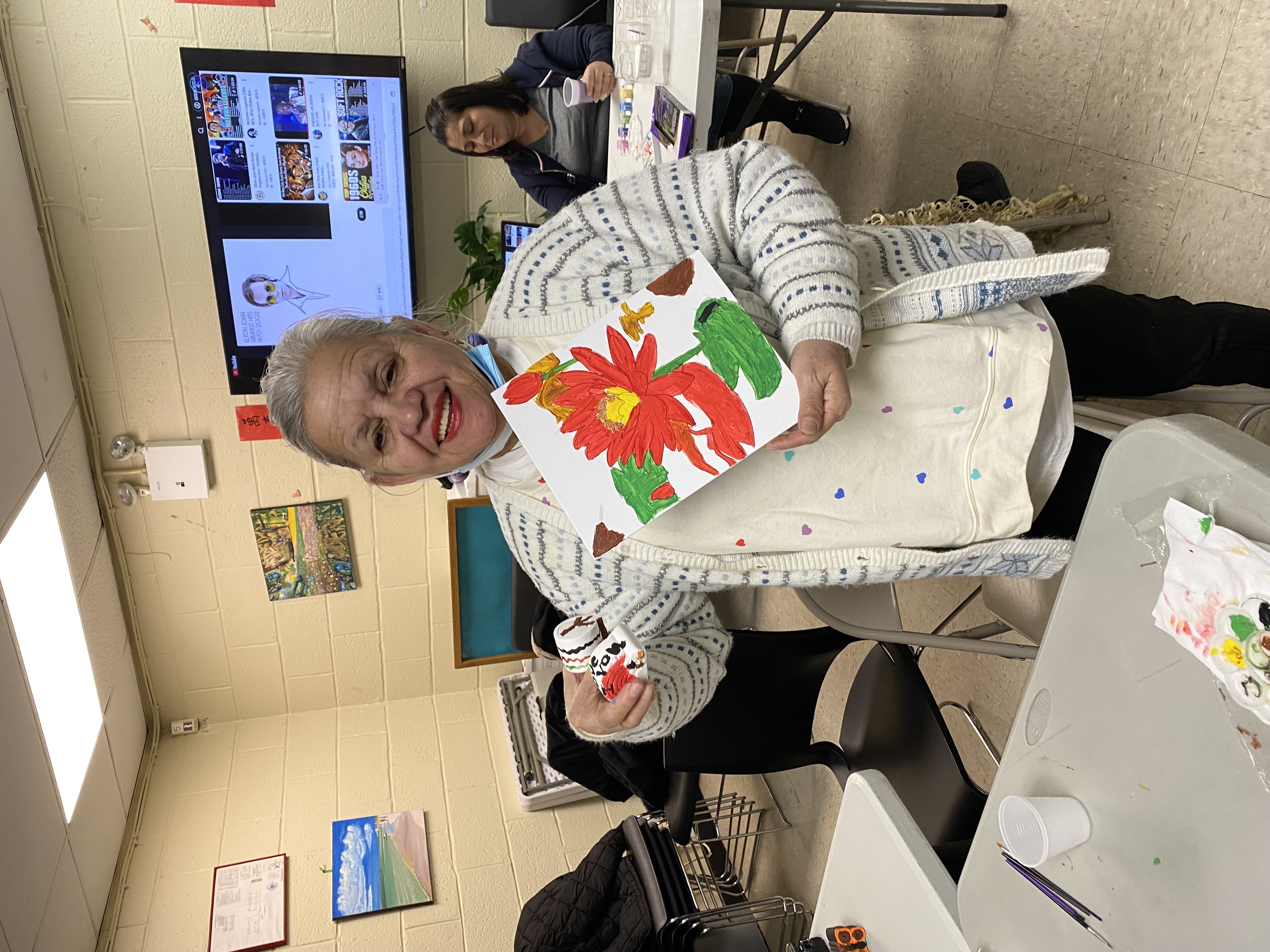 A Senior participant proudly shows us her flower painting.
