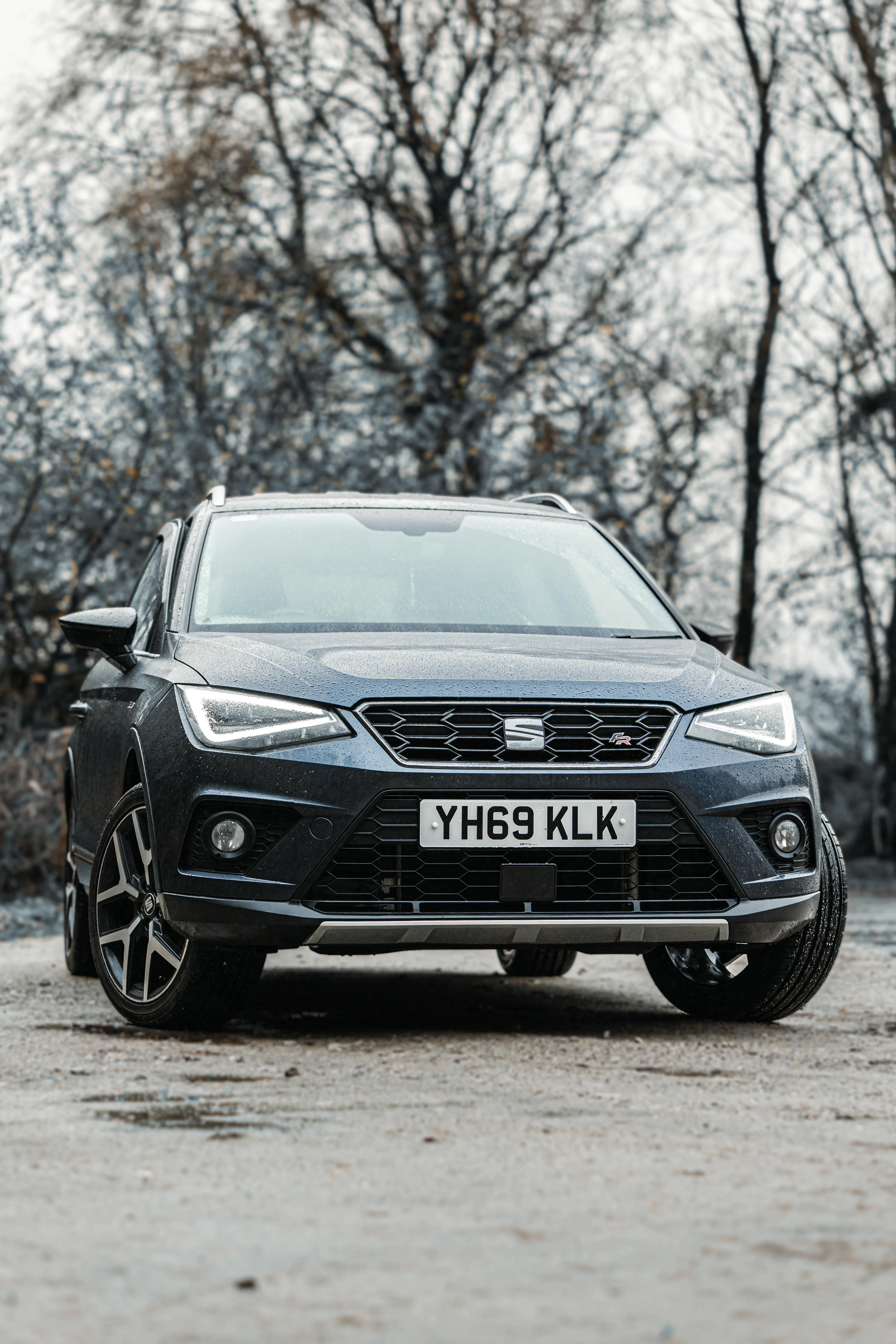 Un SEAT Arona photographié sur sol humide, avec un décor hivernal en arrière-plan. La silhouette du SUV apparaît nette et dynamique, sublimée par les reflets sur la carrosserie et l’ambiance froide qui souligne son côté polyvalent.