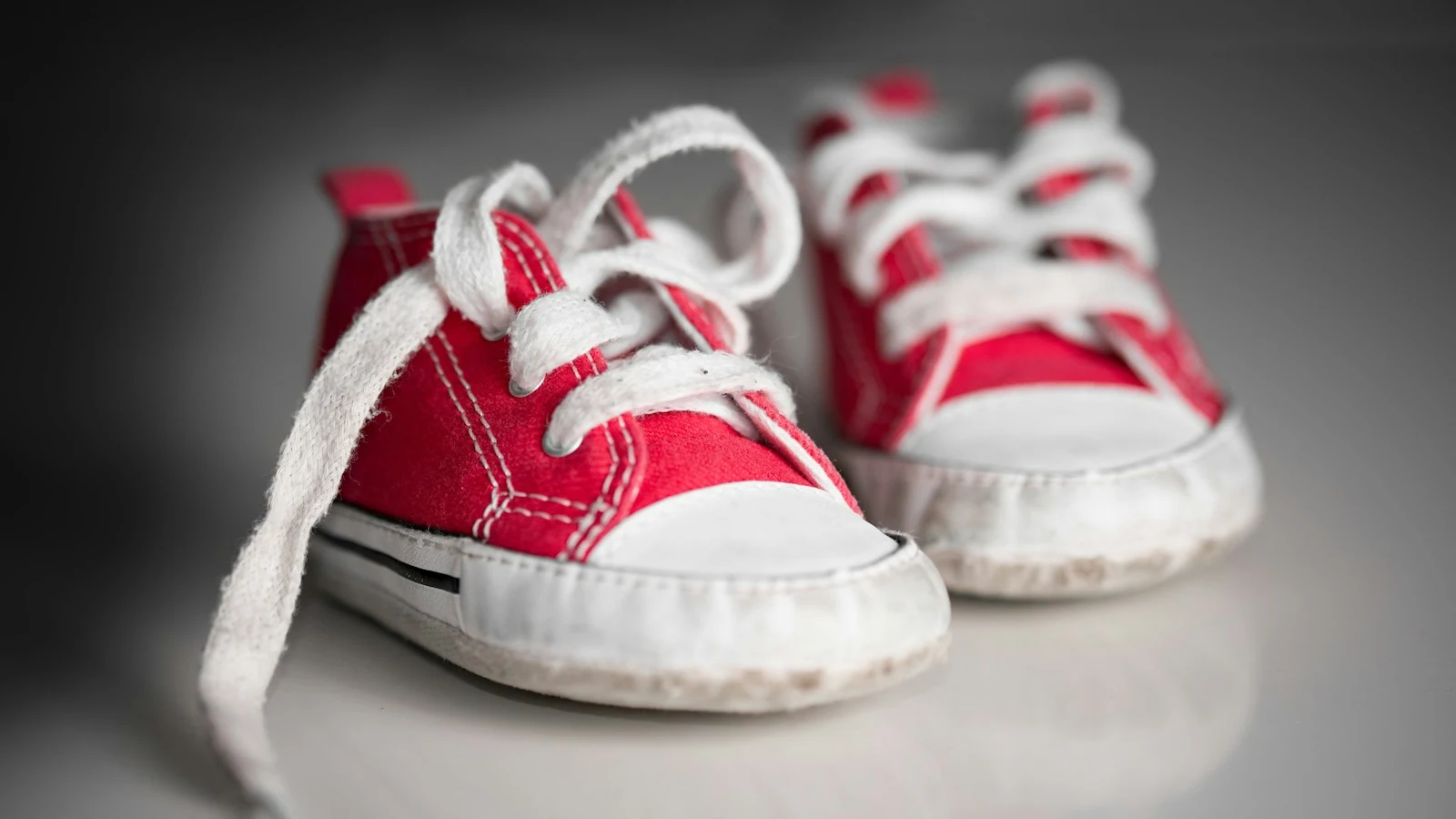 Ein Paar kleine rote Babyschuhe mit weißen Schnürsenkeln