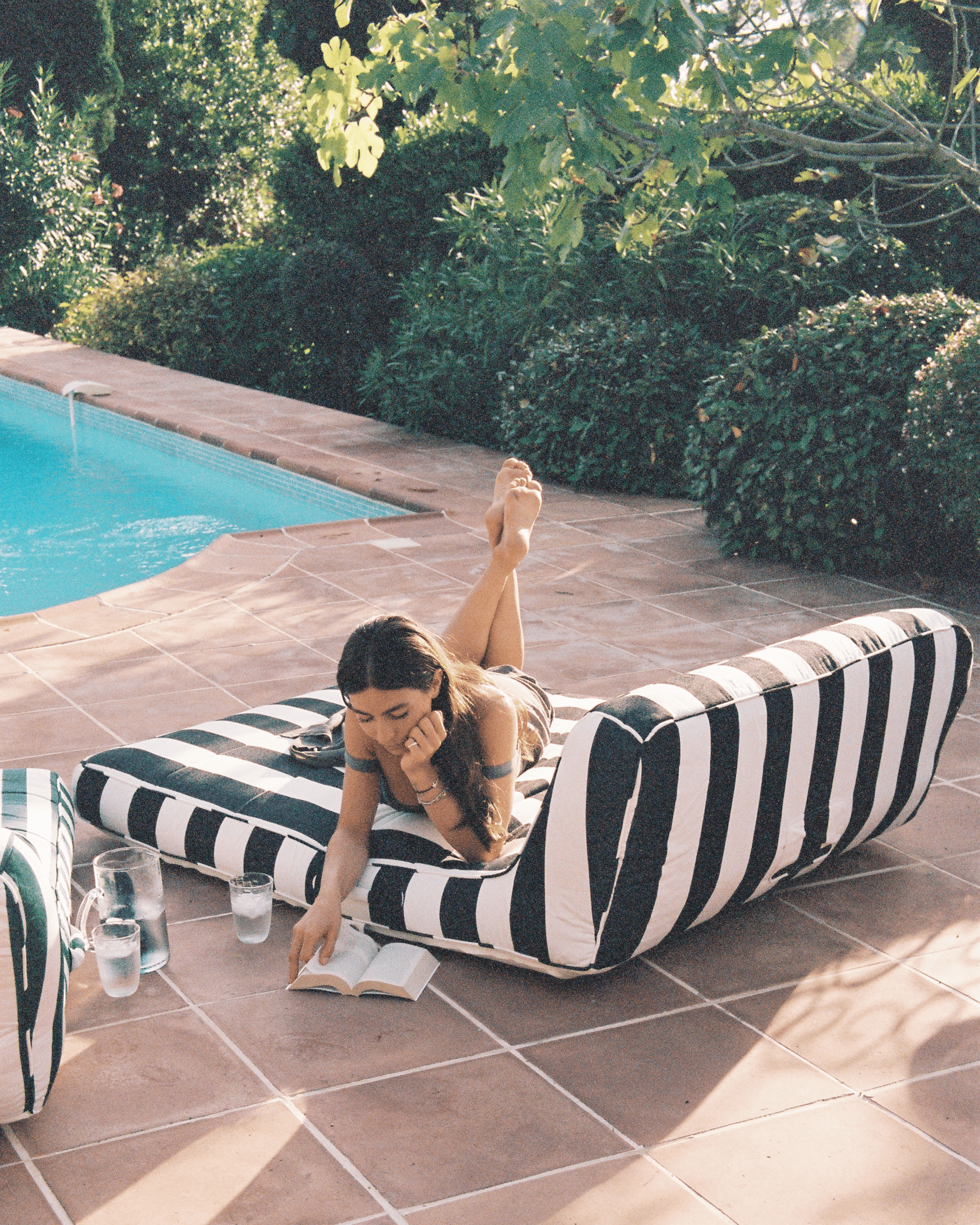 Poolside reading on a black-and-white striped quality lilo used as a plush daybed in a garden setting