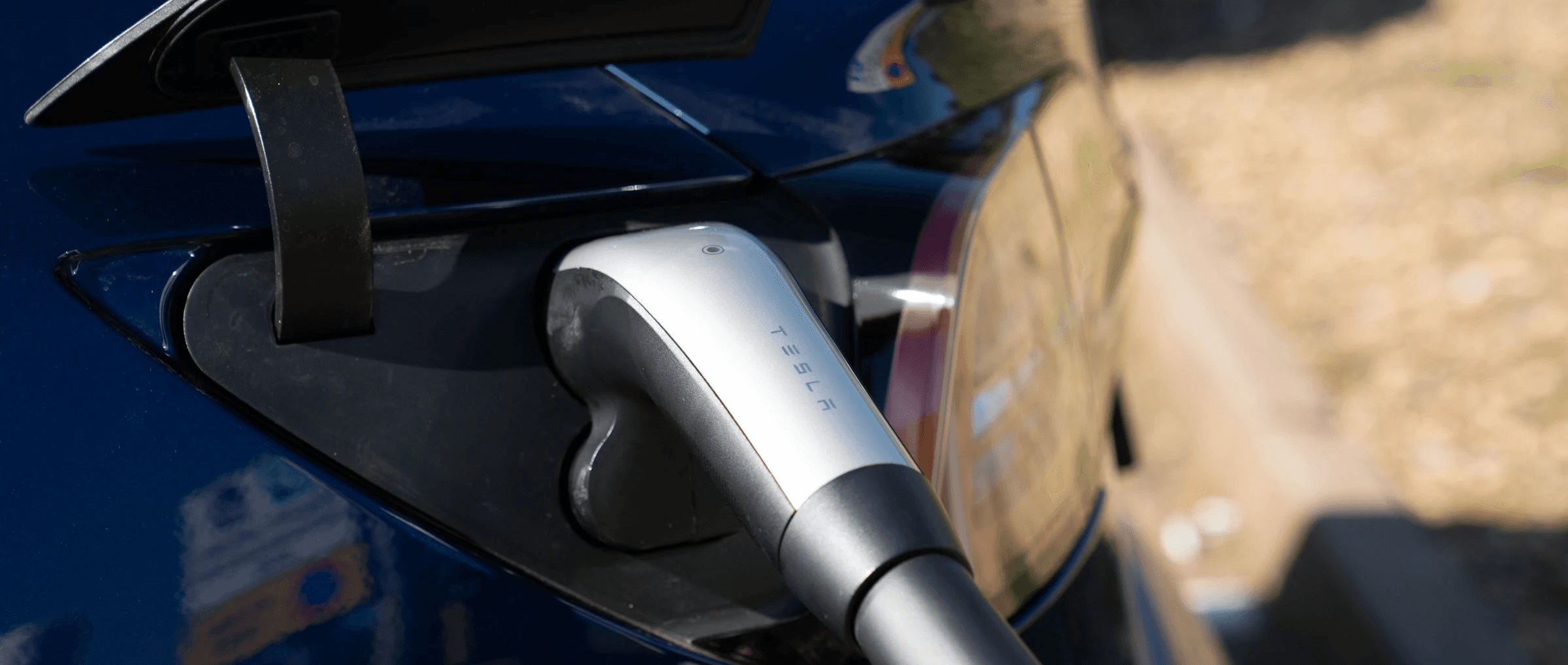 Port de recharge Tesla avec câble branché, détail d’une voiture électrique en cours de charge