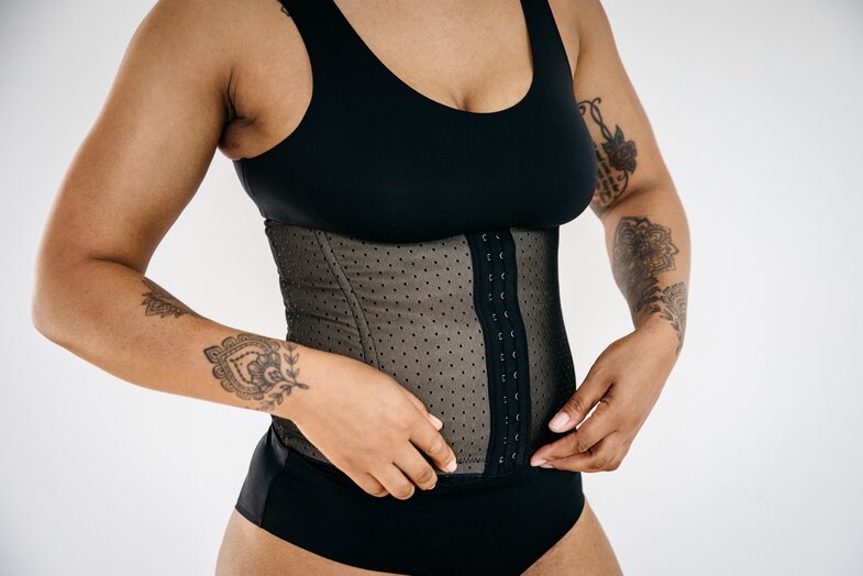 Woman in black activewear and waist trainer for fitness.