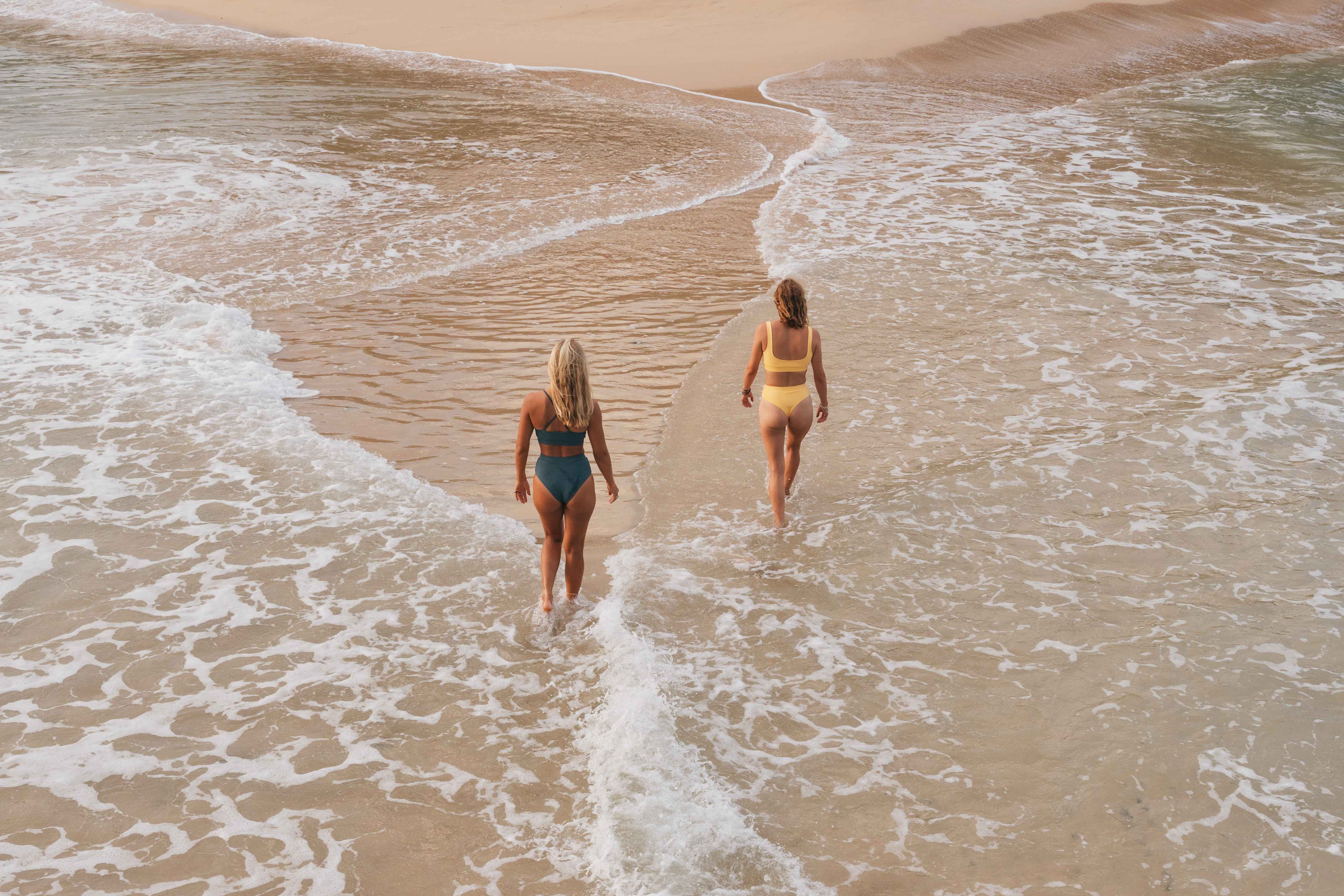 Two girls in bikini walking at the beach 