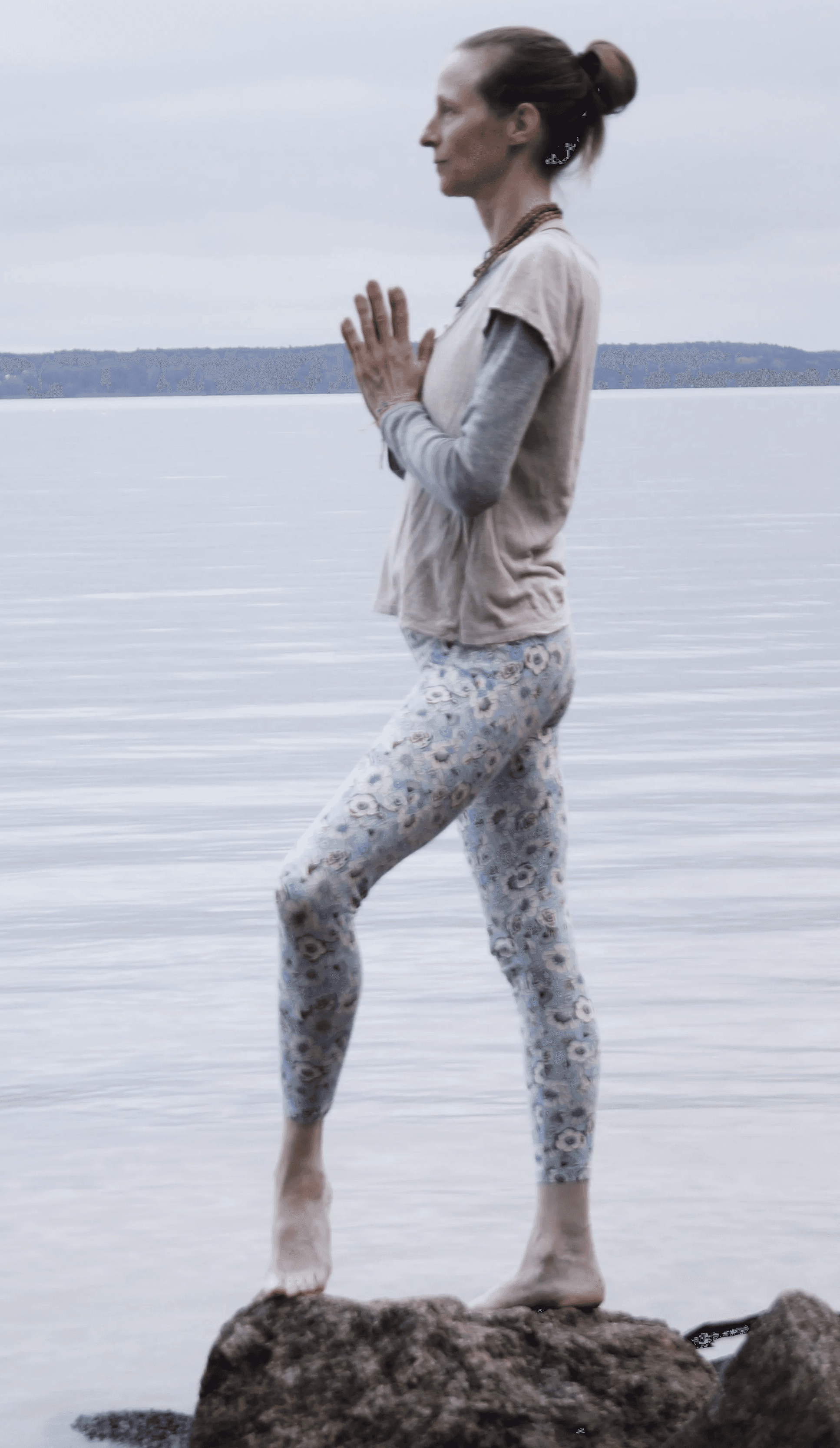 Karina Gaurangi Schmuck ist aufrecht stehend auf einem Stein, mit dem linken Bein einen kleinen Schritt nach vorne (Bein ist leicht gebeugt) und Anjali Mudra (Handflächen aneinander gelegt) vor dem Herzen