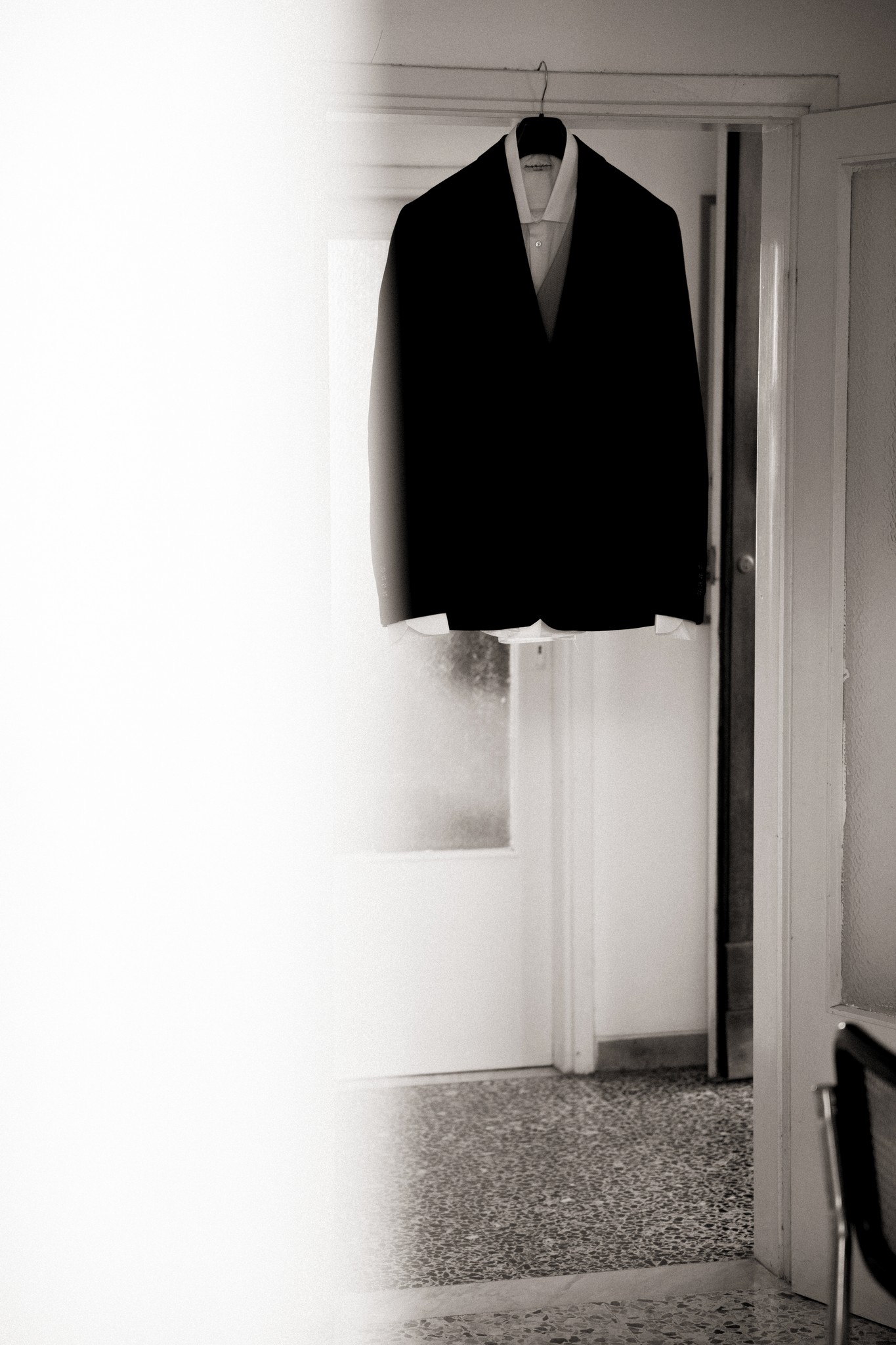 Giacca nera dello sposo appesa su hangers, preparativi di matrimonio a Bolgheri in bianco e nero