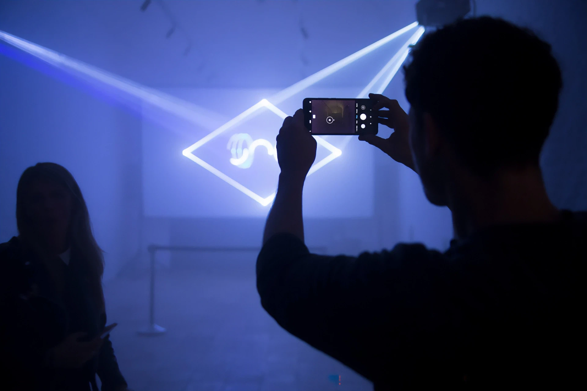 Man photographs glowing diamond sculpture with phone