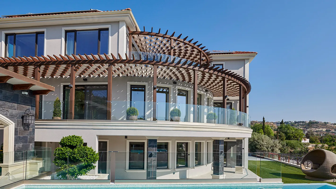 Villa Belmare rear elevation with curved pergola terrace, glass balustrade, and modern poolside façade
