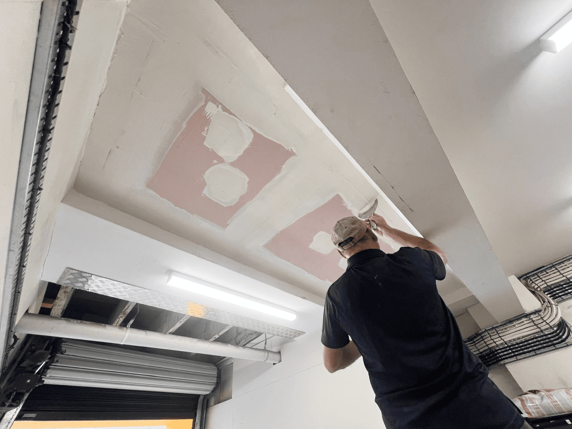 Man patching a ceiling with white plaster.