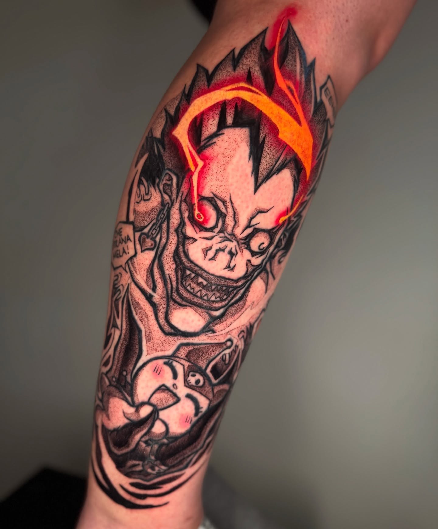 A grayscale anime-style tattoo of a character with spiky hair and a headband, holding a kunai.  The tattoo is on someone's forearm.