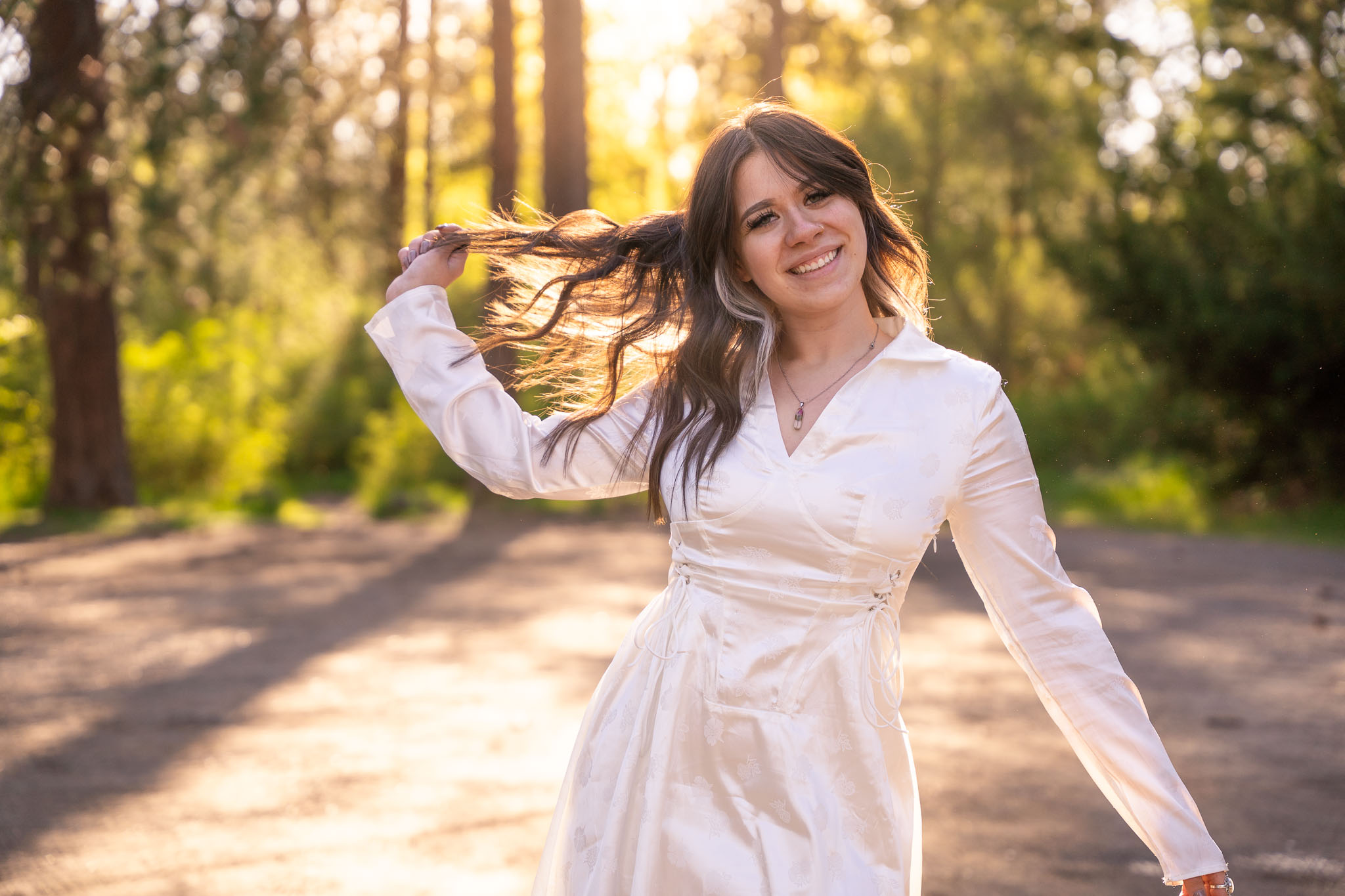 A sundressed image of a woman dancing in a white dress, pulling on her hair