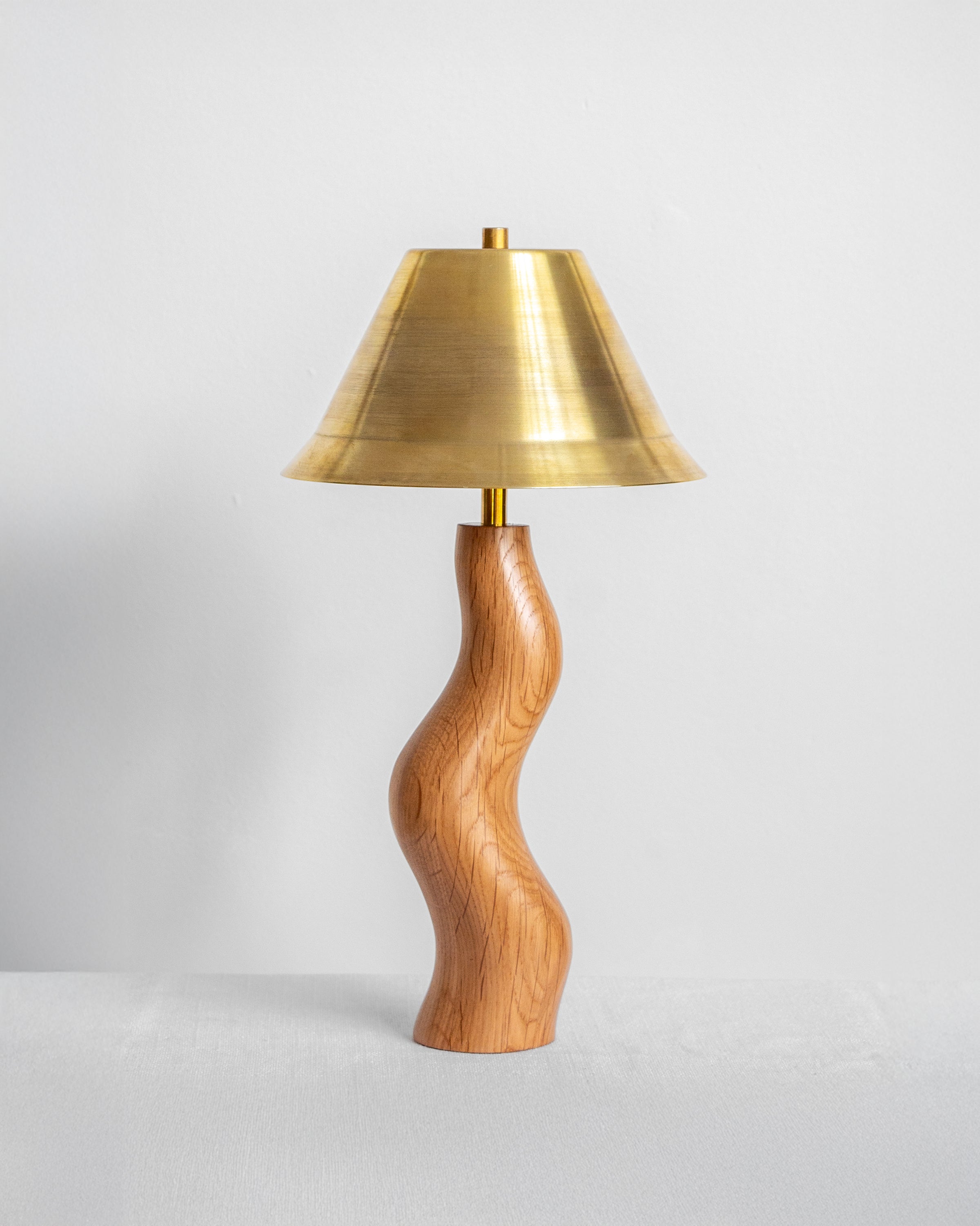 Dancing Desk Lamp with Oak base and Brass shade on a light grey with UK, EU and US/CA wiring available Wilkinson & Riverabackground