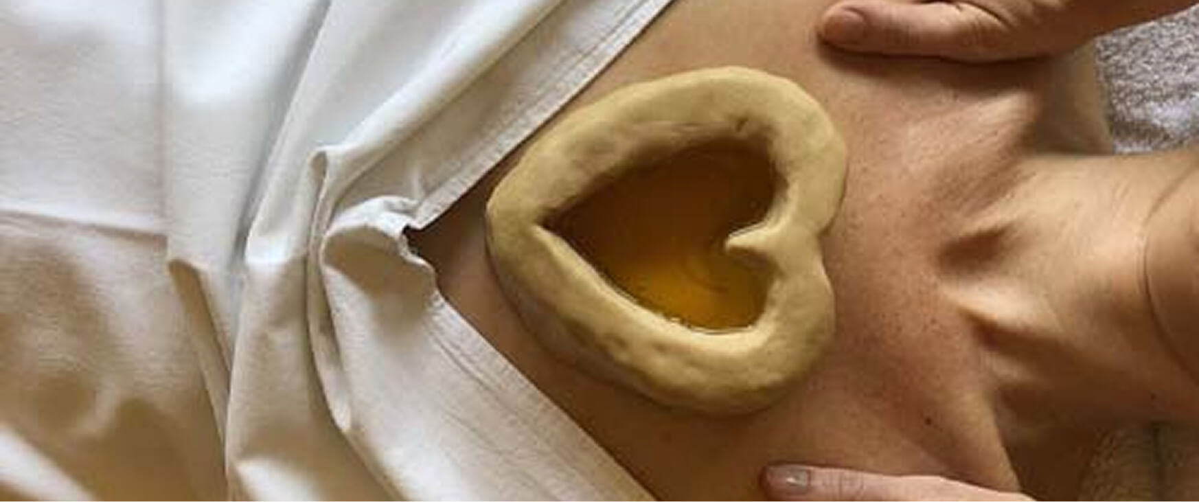 A therapeutic procedure shows a heart-shaped dough dam placed over the chest, filled with warm herbal oil, demonstrating the benefits of Hridaya Basti for heart health and relaxation.