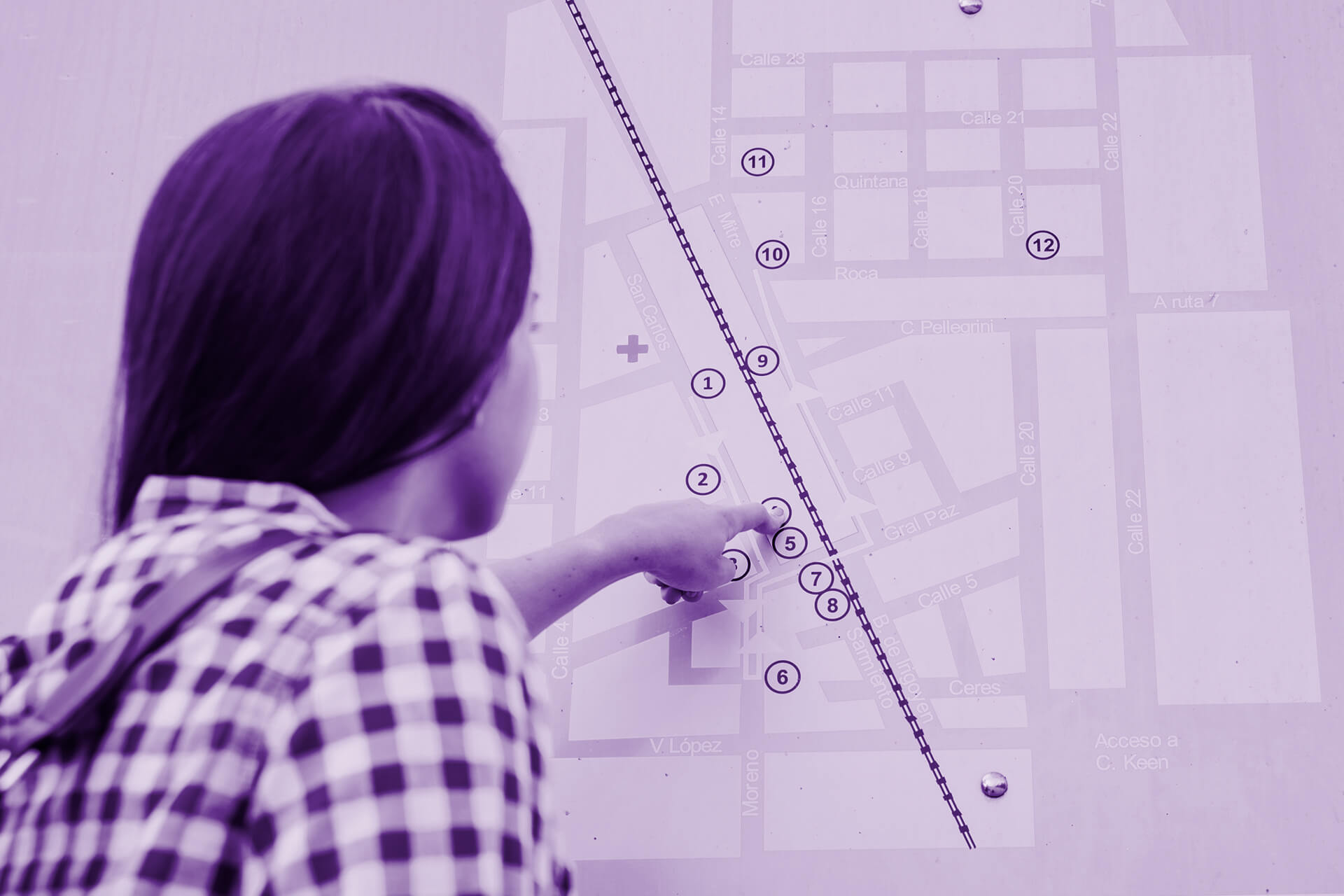 Someone pointing at a printed map sign, viewed from behind, back of head and shoulders visible