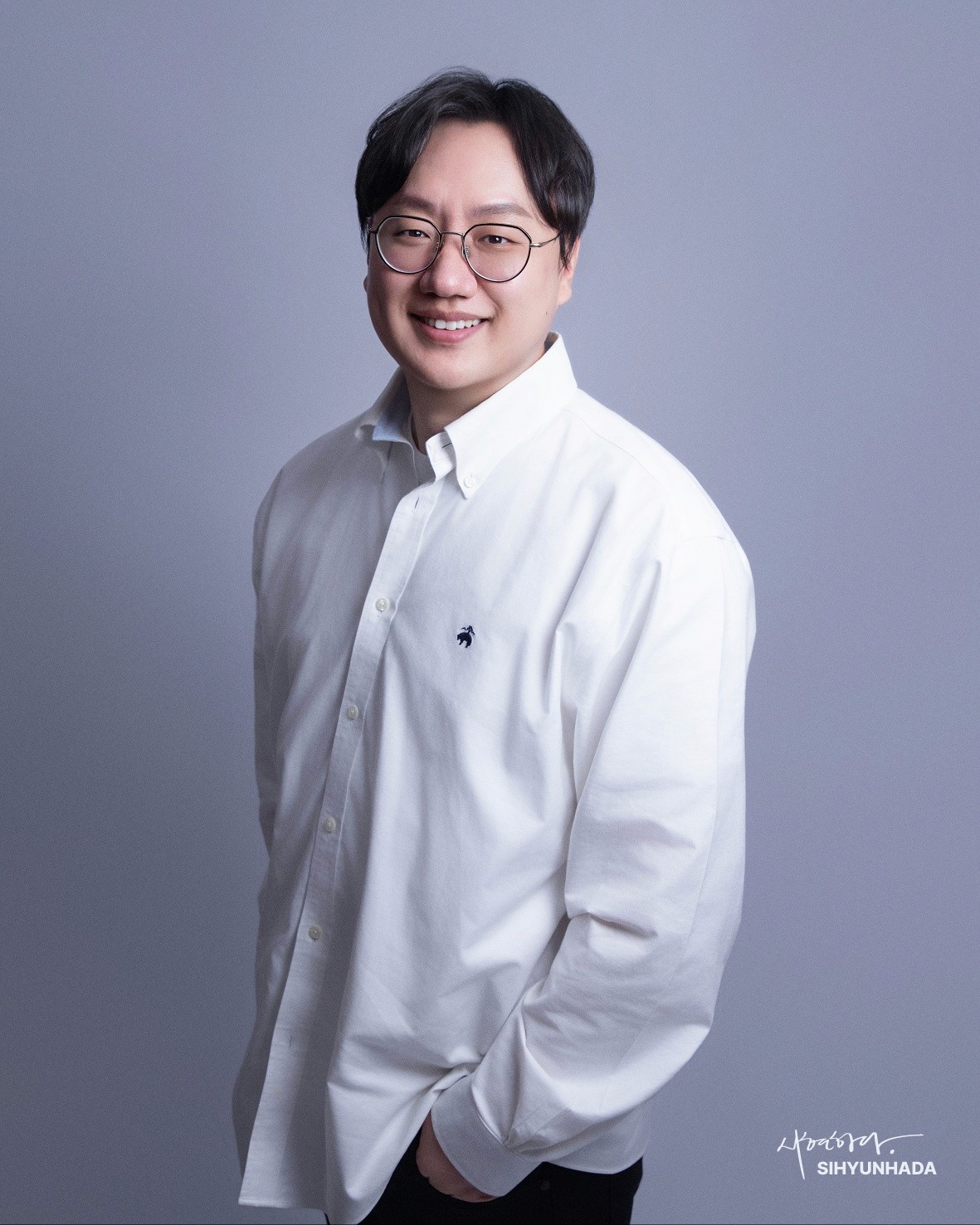 Portrait of a person in a pink sweater against a light background