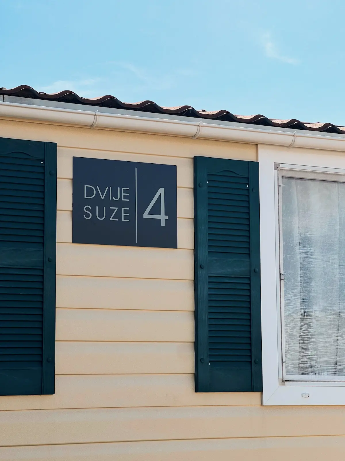 Pročelje mobilne kućice Dvije Suze 4 sa zelenim grilijama i znakom kuće