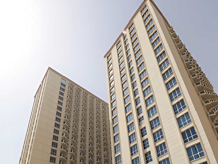 An unobstructed road leads to a skyline featuring tall buildings, prominently including Lakeside Tower