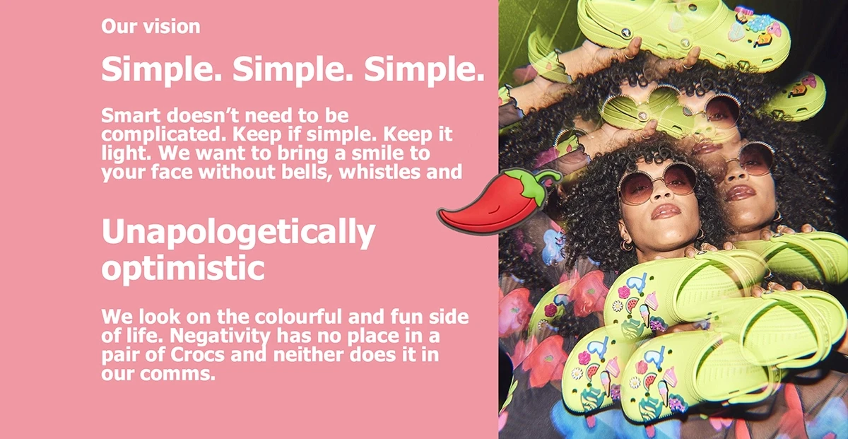 Crocs brand vision page displaying 'Simple. Simple. Simple.' and 'Unapologetically Optimistic' brand values alongside editorial image of woman lying among neon yellow Classic Clogs decorated with Jibbitz charms on pink background