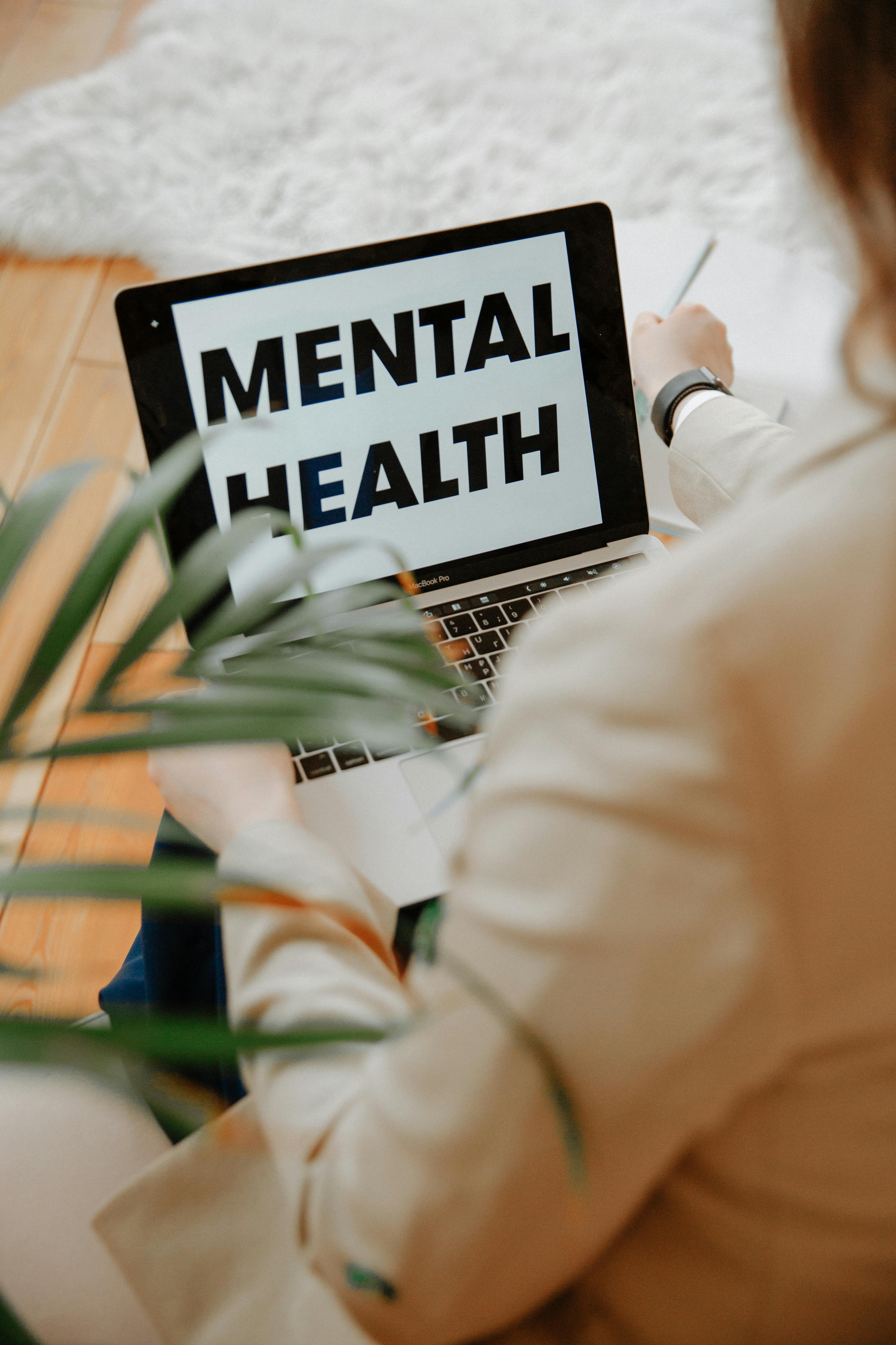 Persona sentada con una laptop con el mensaje de salud mental en pantalla