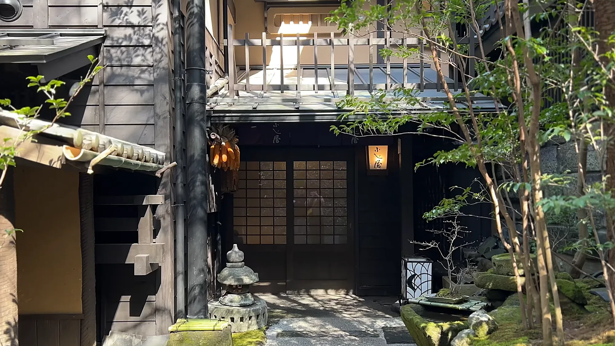 A dark timber inn entrance at Kurokawa Onsen with a lantern and a stone basin