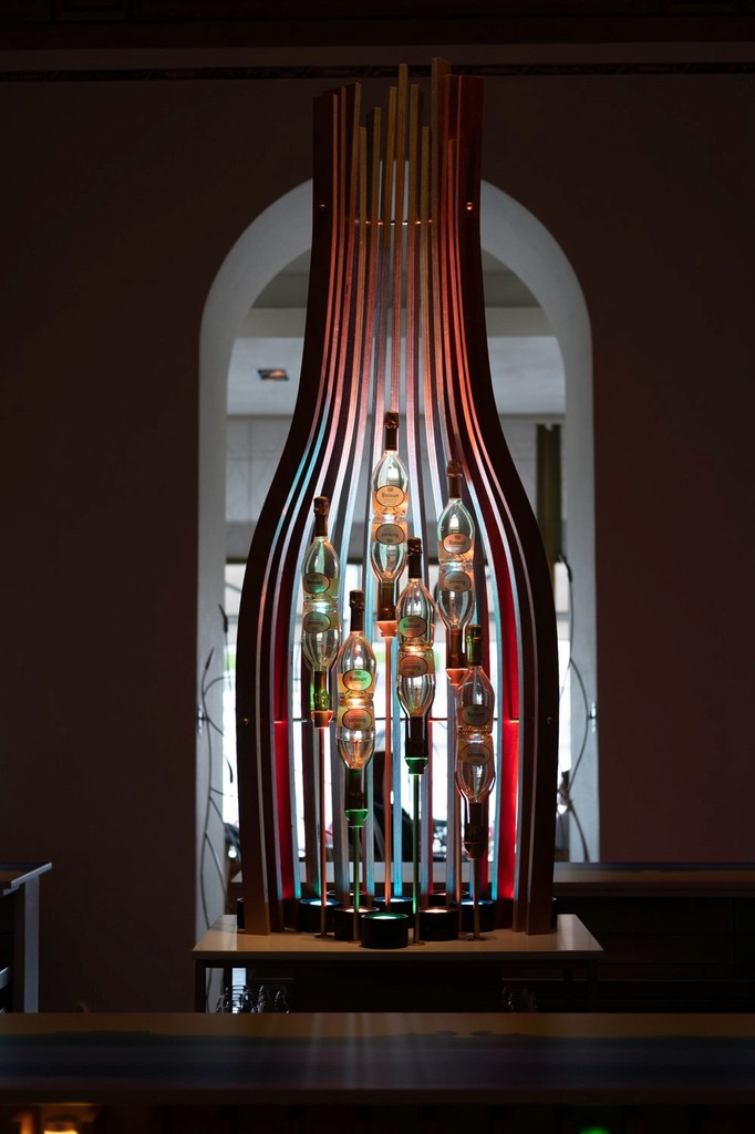 Decorative display of bottles arranged vertically inside a wooden frame with colorful backlighting.