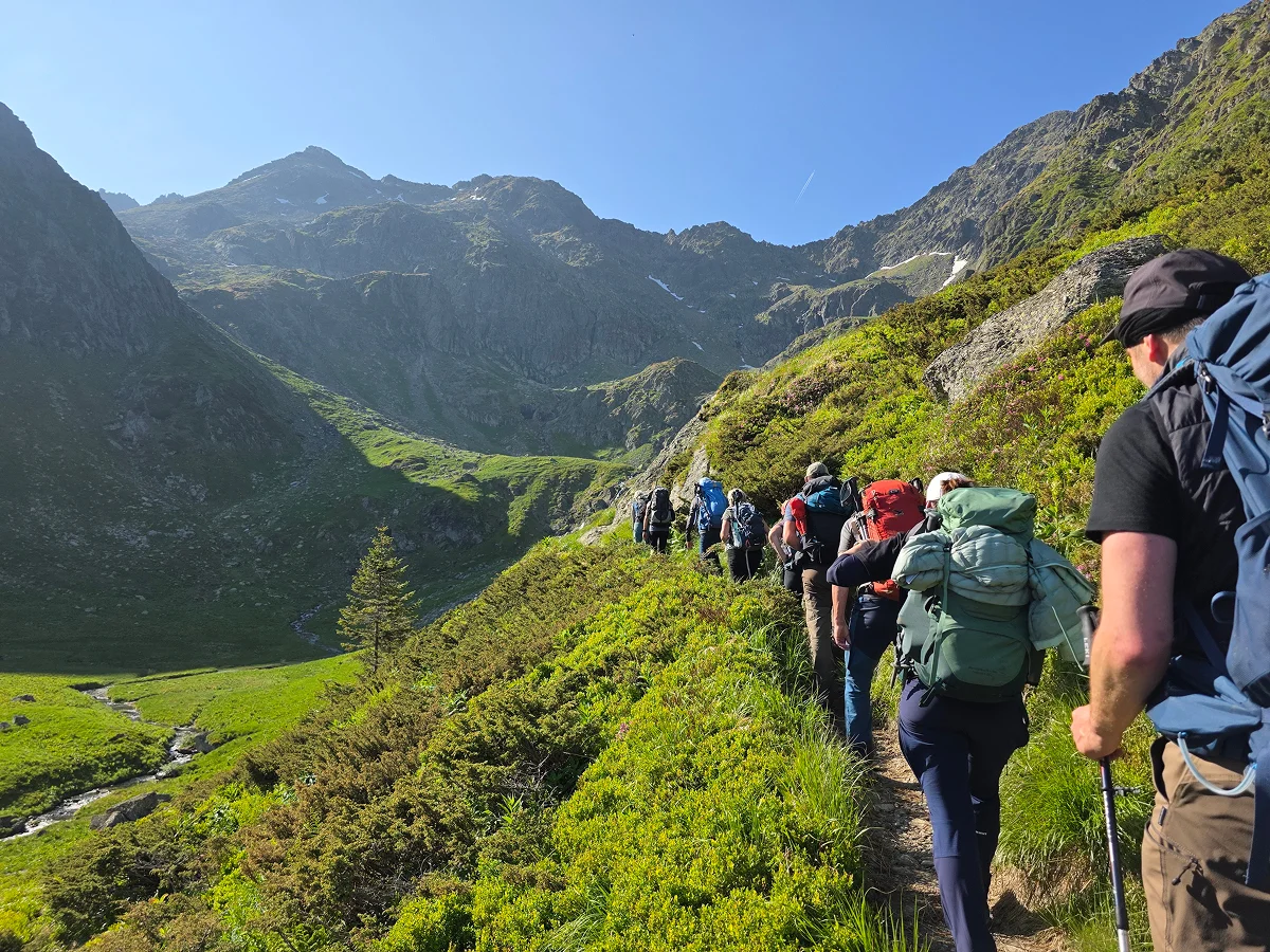 Reisegruppe wandert am Berghang mit Block ins Tal