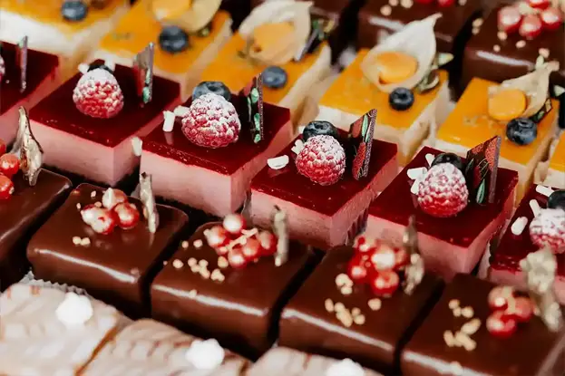 A colorful bowl with avocado, mixed vegetables, and chicken, accompanied by a side of greens and an orange.