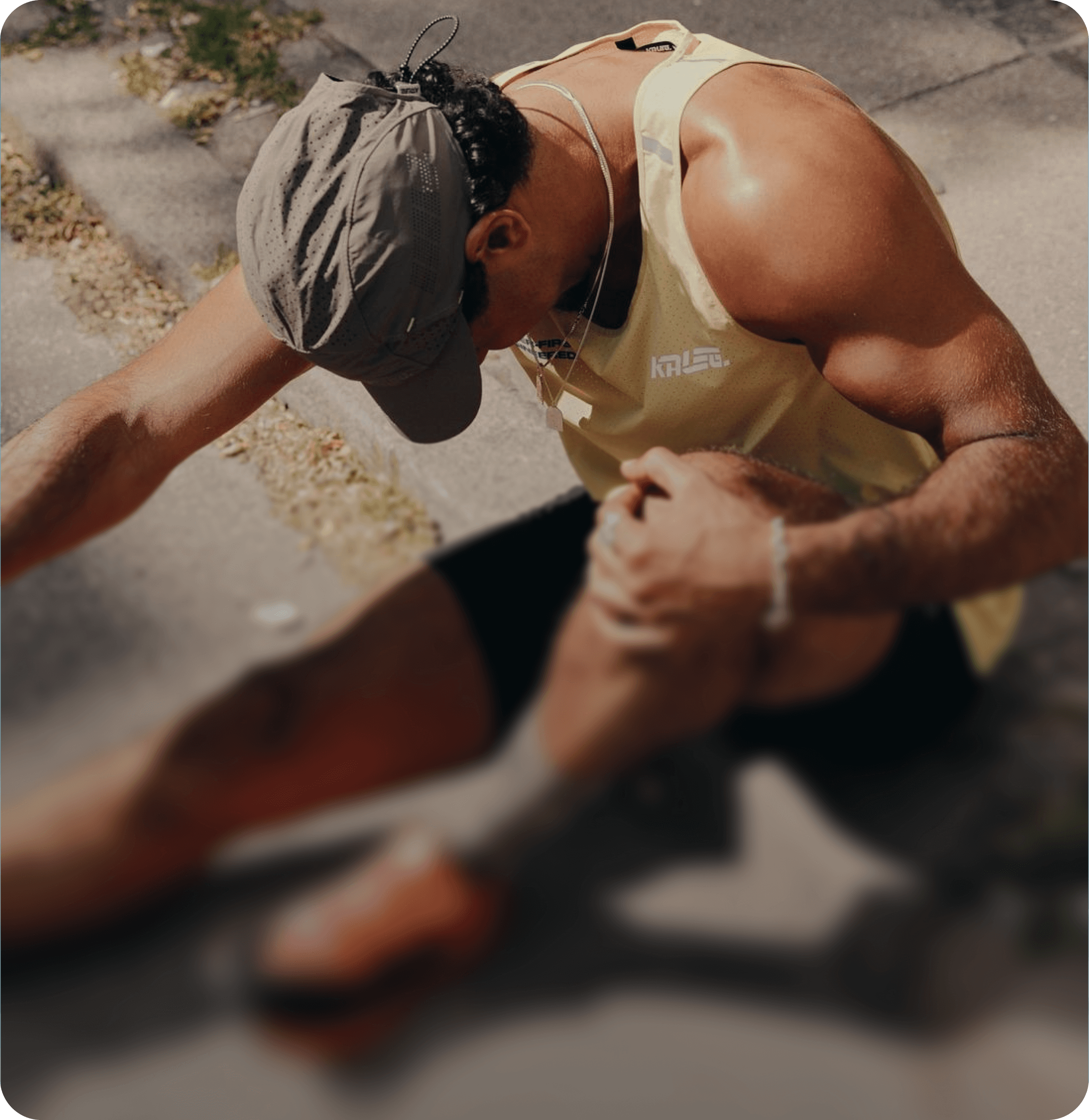 Man sitting on the ground outdoors stretching his leg