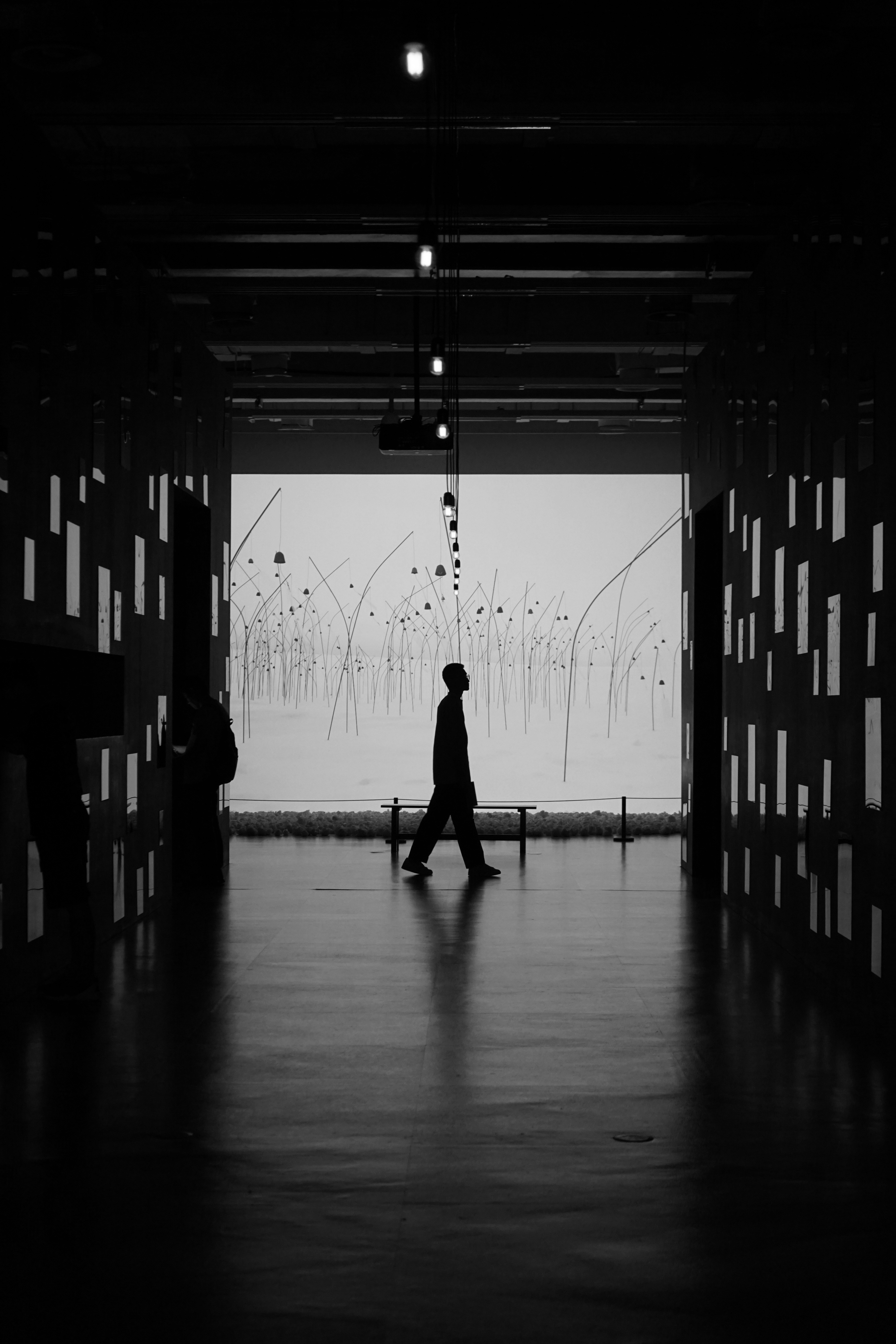 A black and white photo of a person walking in a dark room